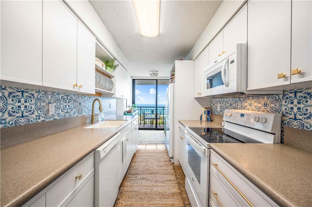 Bright & clean galley kitchen overlooking the ocean.  **Beaded flush mount fixture does not convey.**