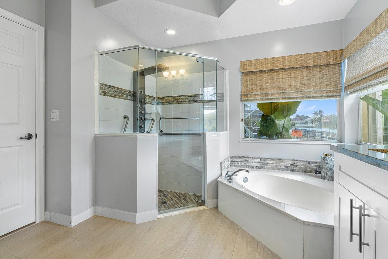Primary bathroom boasts seemless shower doors, tv hookup, top of the line cabinetry and countertops