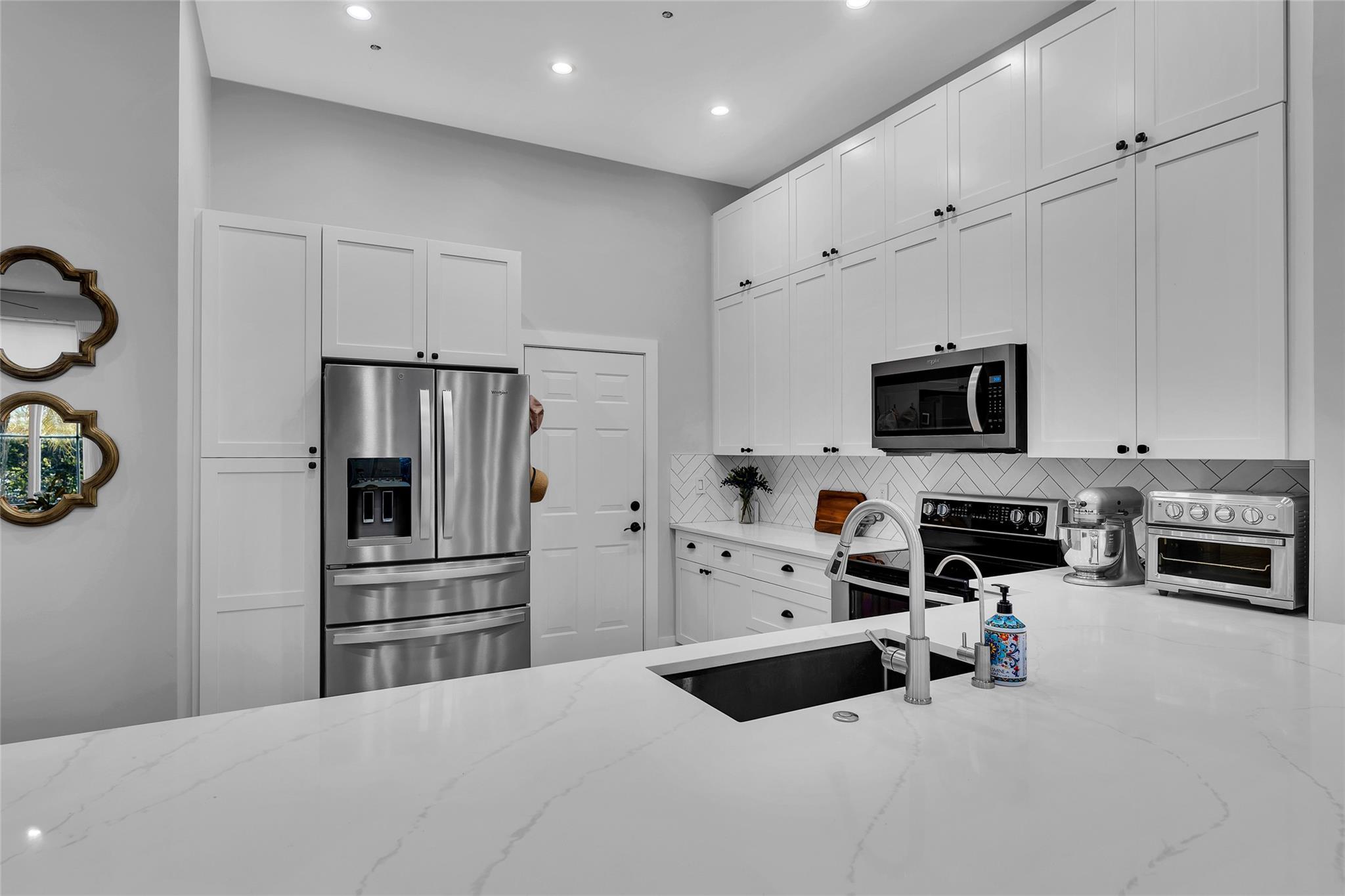 White shaker cabinets and quartz counters with stainless steel appliances