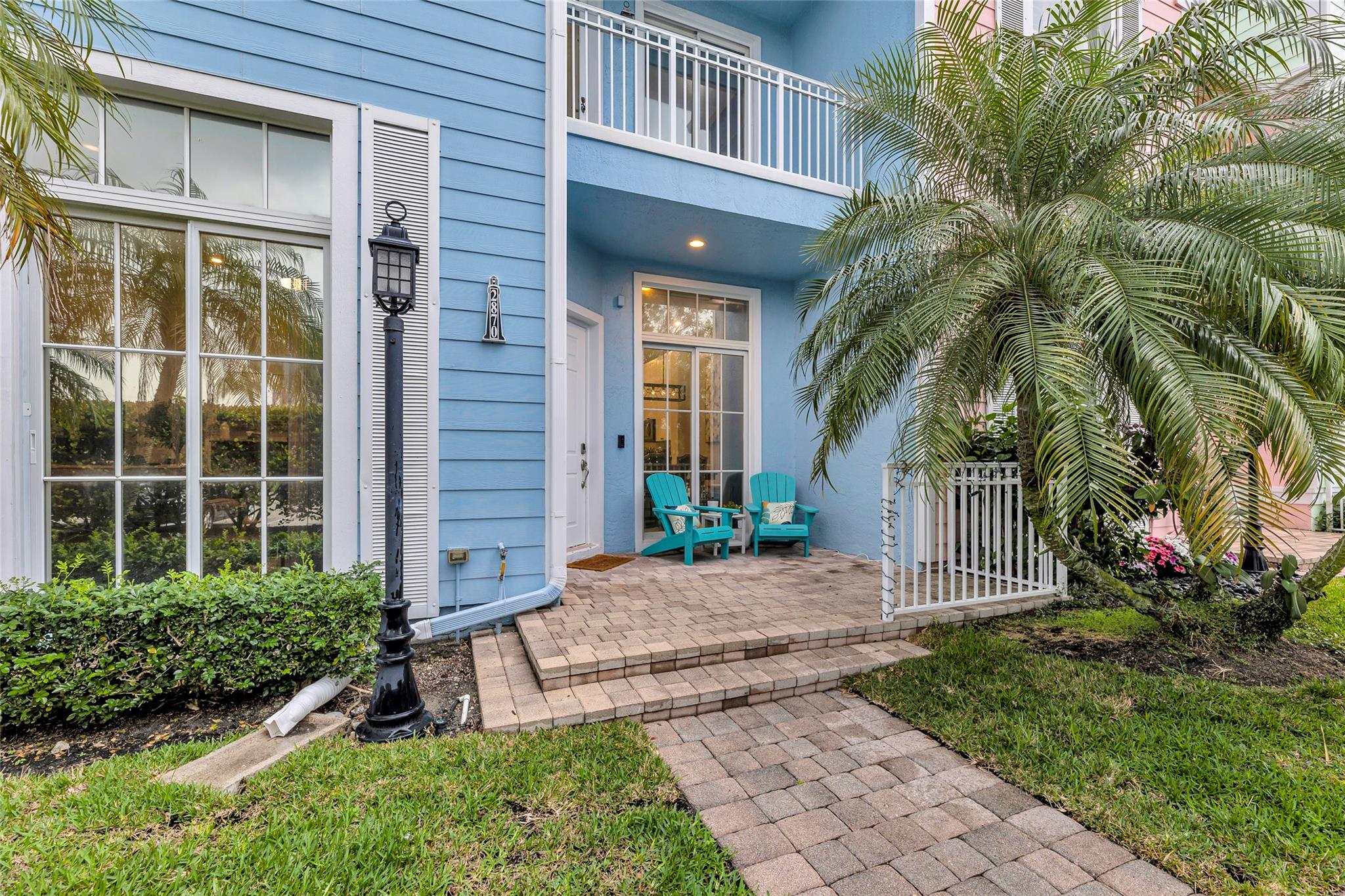 Charming Key West style townhome with pavered front porch and surrounded by tropical landscaping