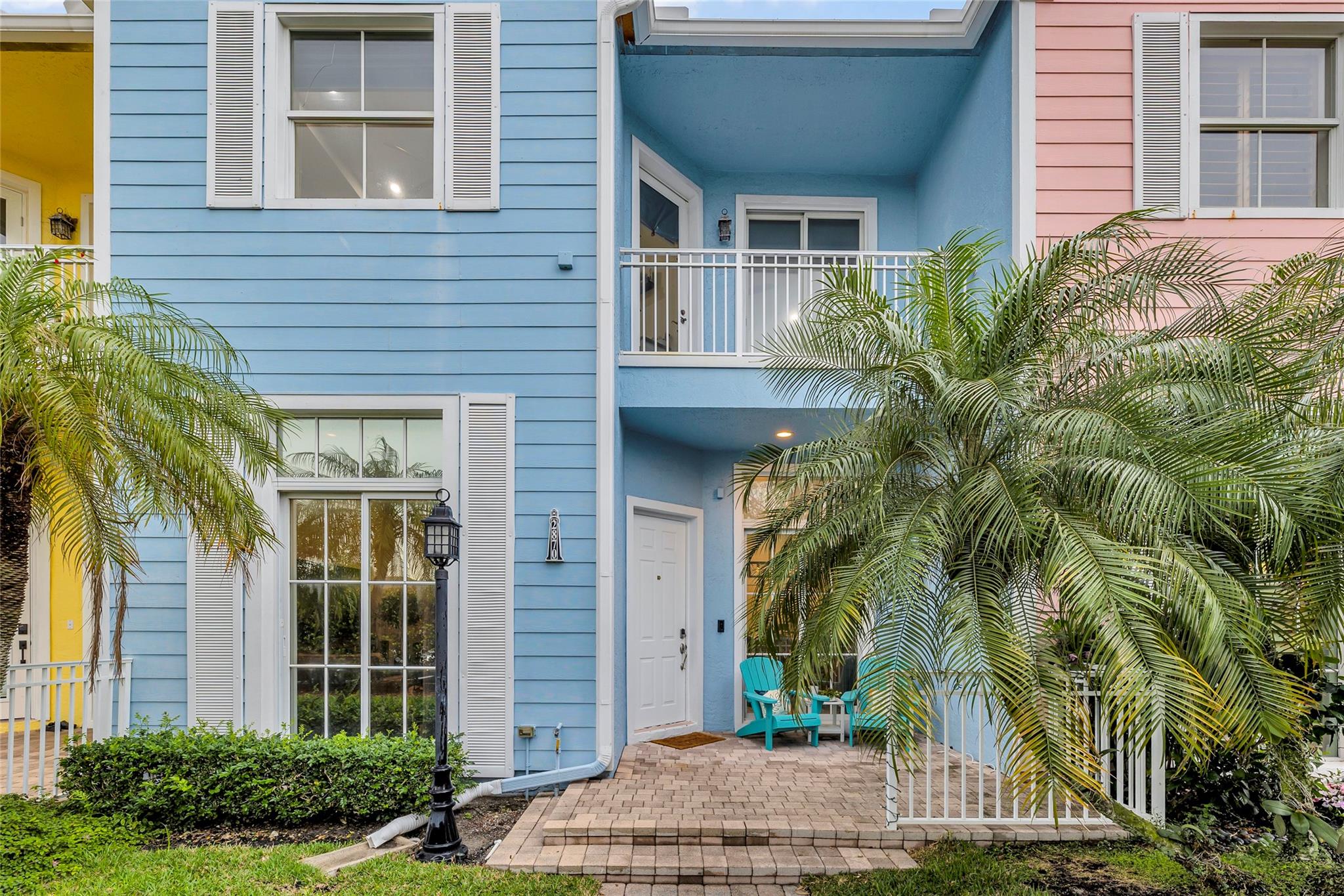 Key West style townhome with pavered front porch and surrounded by tropical landscaping