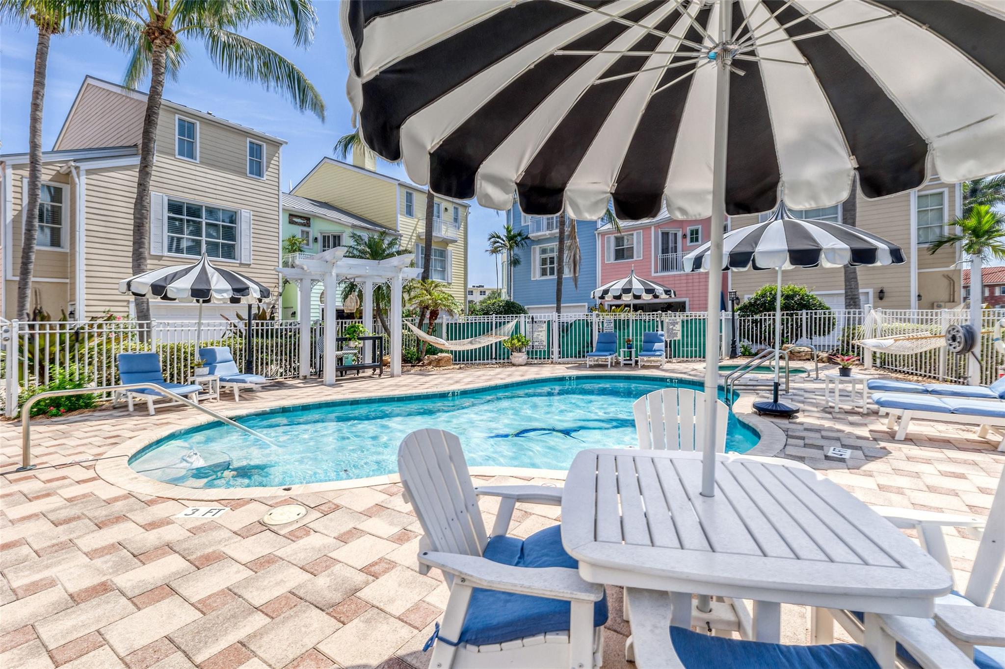 Pavered pool deck offers lounge chairs, tables, hammocks, fire pit and more