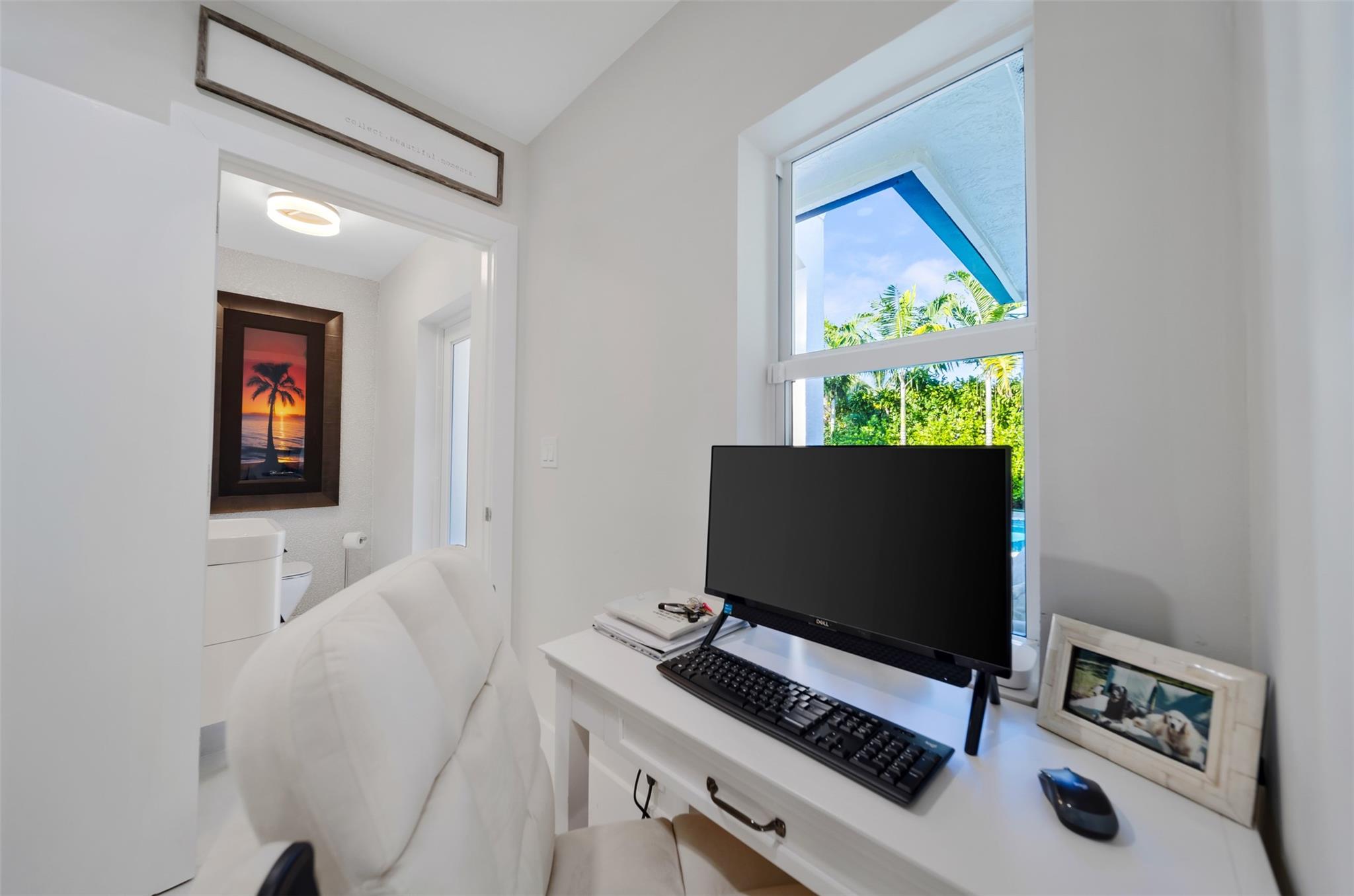 hallway nook with small home office set up, door to cabana bathroom leading to the pool. ( garage door right behind and hallway leading to laundry room.