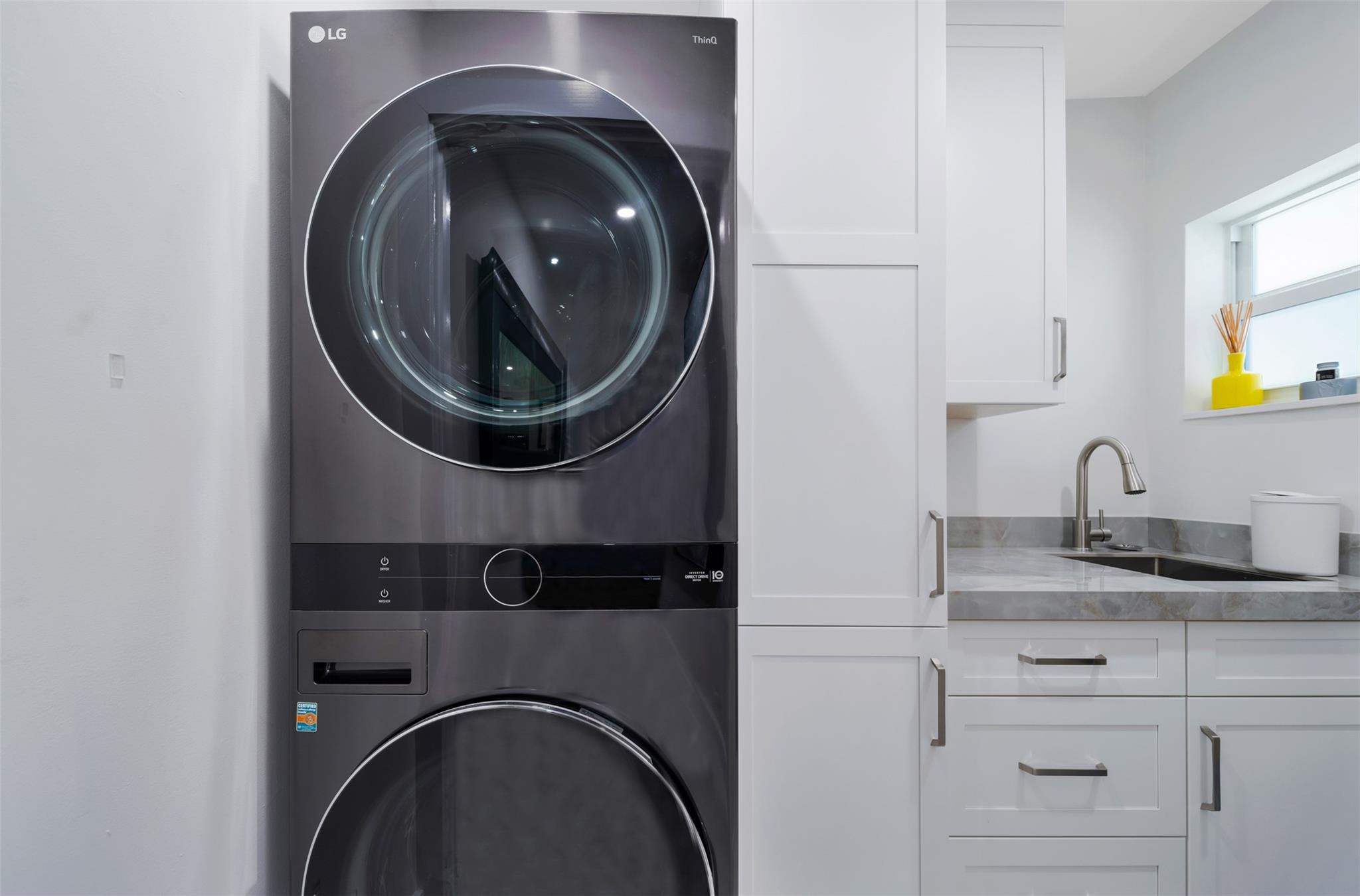 Full laundry room with new LG washer & dryer, cabinets with extra storage and laundry sink.