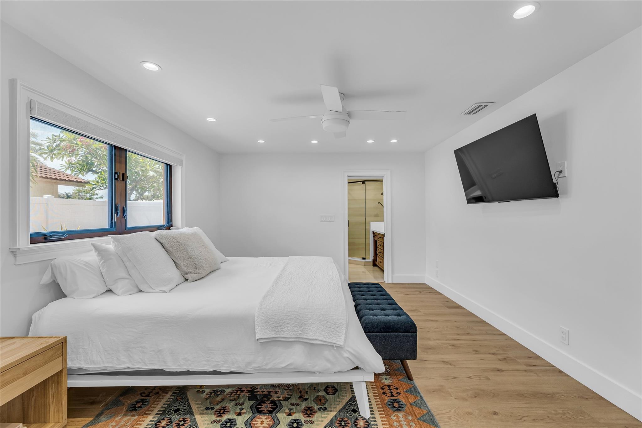 Master bedroom offers an abundance of natural light with electric shades, high-hat lighting and wood plank tile flooring