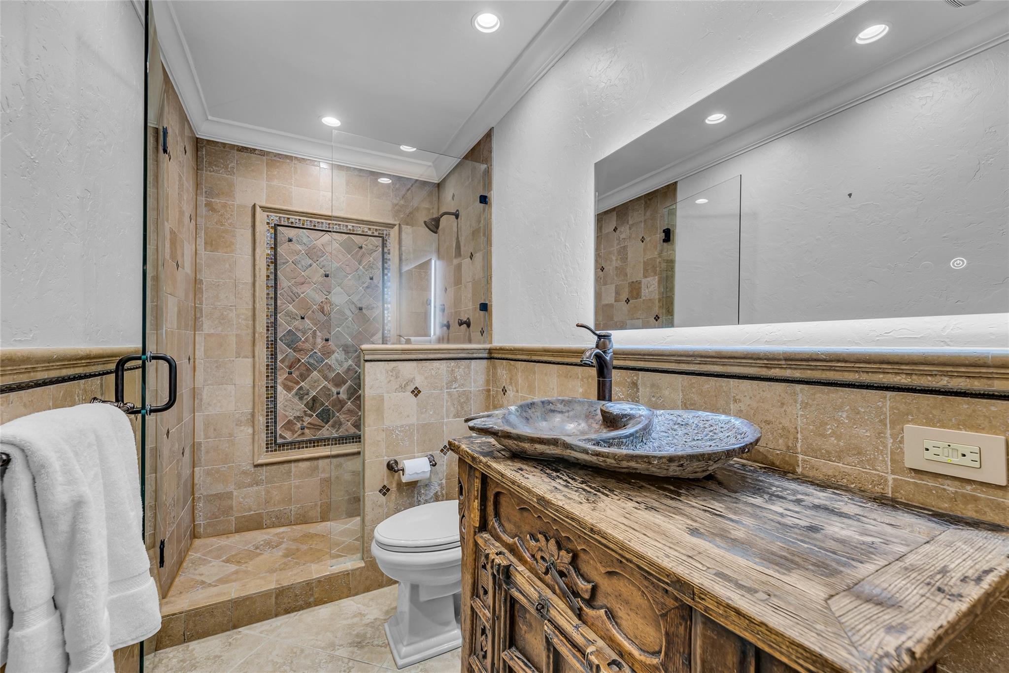 Third bathroom with Travertine walk in shower, custom wood vanity and custom stone sink with oil rubbed bronze accents