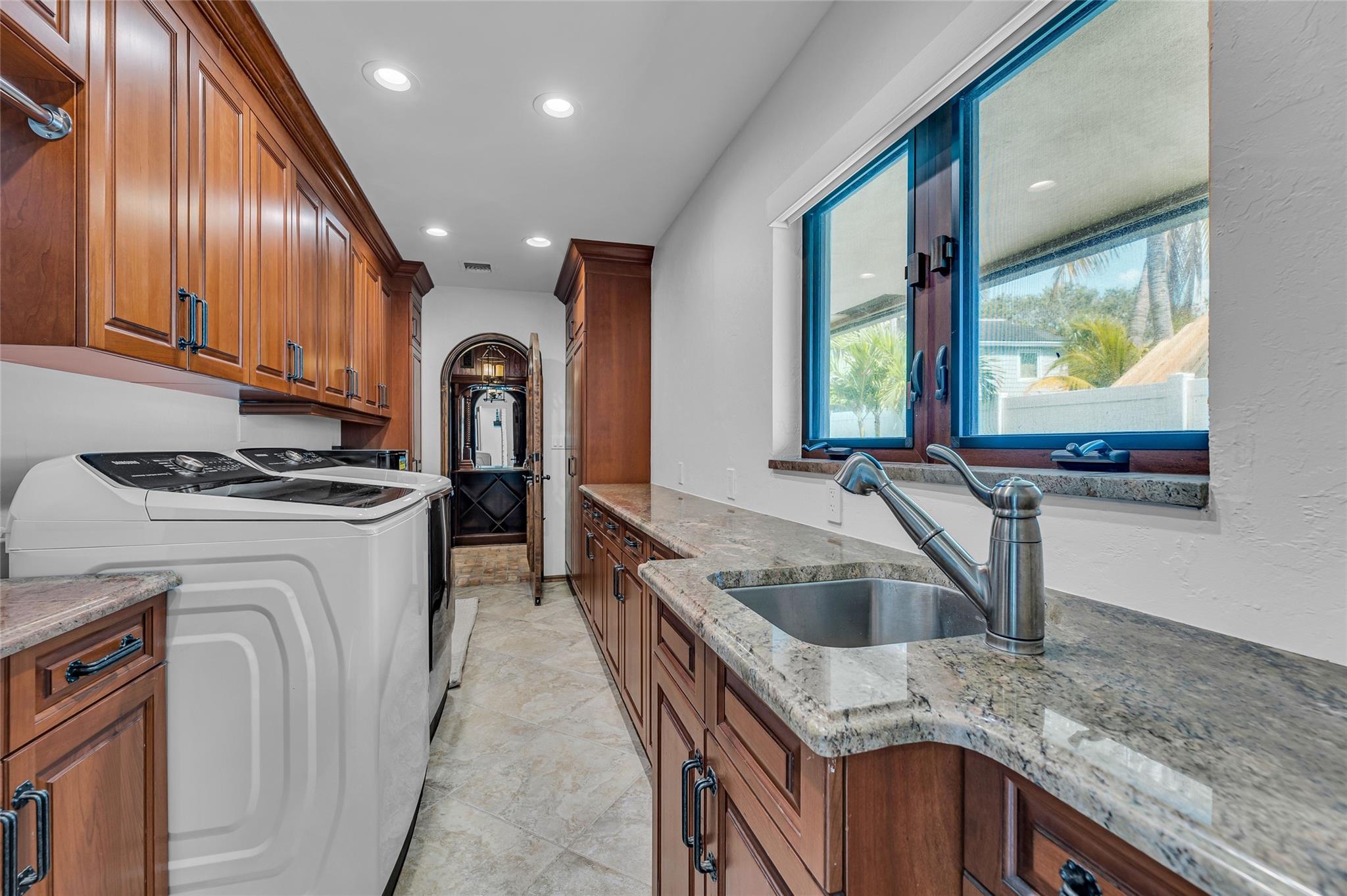 Huge laundry room with new Samsung washer and dryer, wood cabinets that offer tons of storage, Utility sink and window offers great natural light