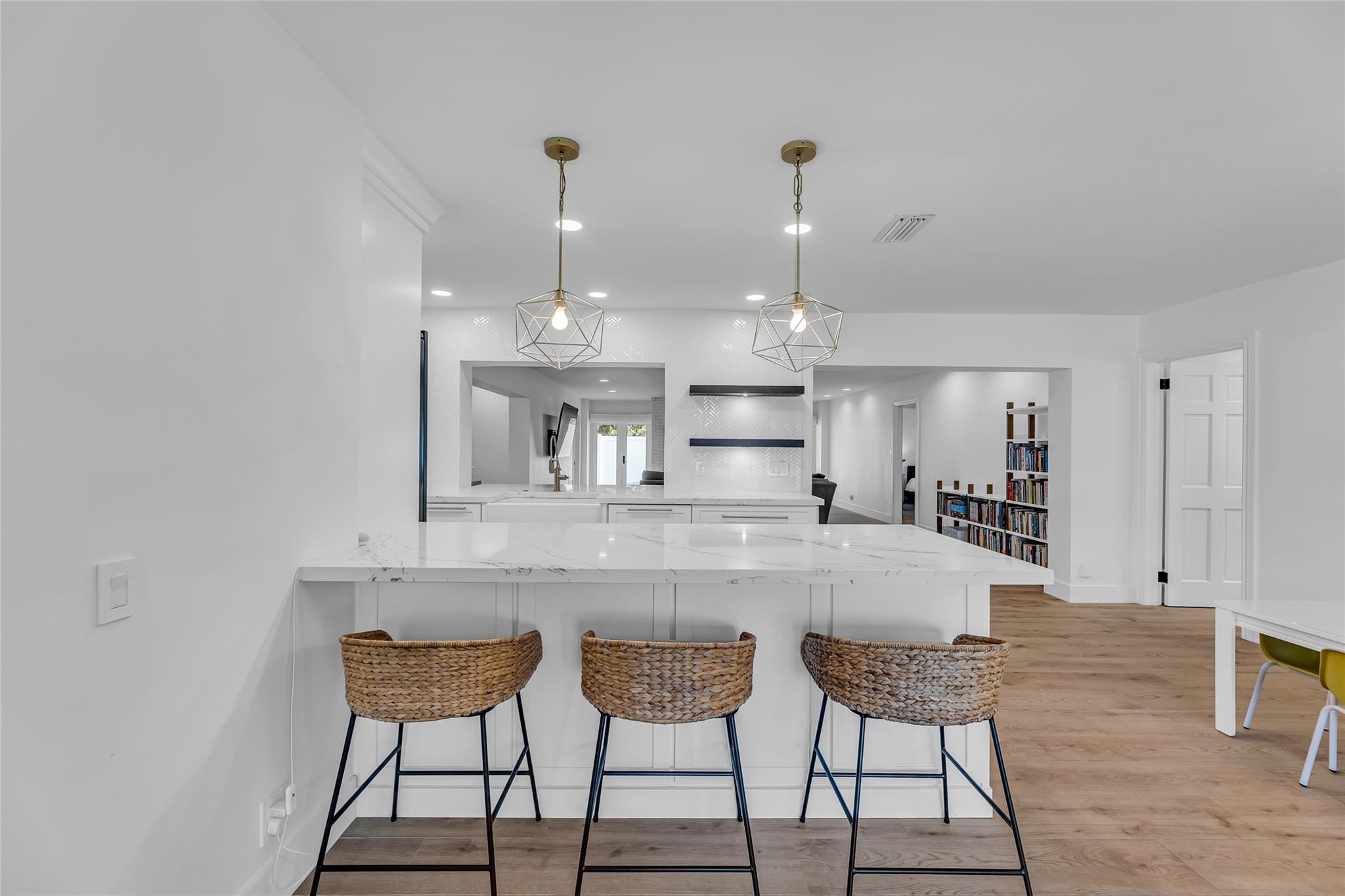 Breakfast bar with thick quartz counters is shared with kitchen and living room space