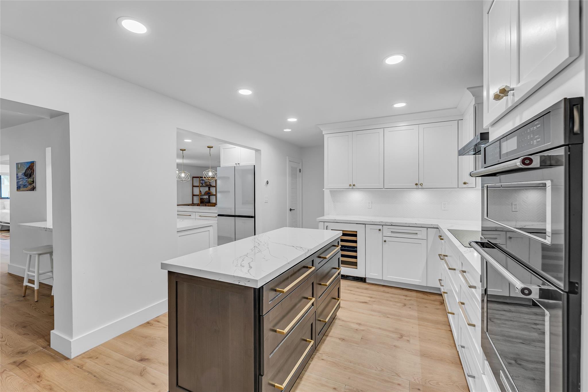 New kitchen features center island, white wood cabinets, thick quartz counters, White chevron backsplash tile and an abundance of storage space