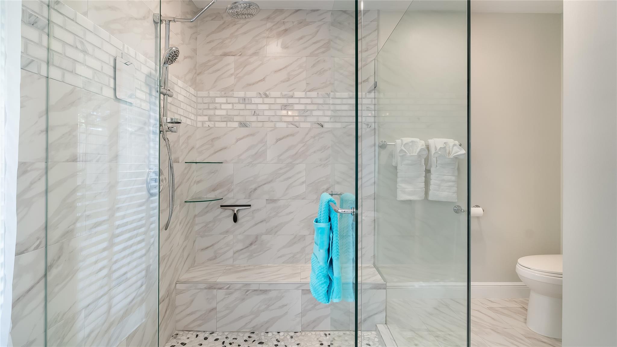 The oversized frameless glass shower boasts massaging body jets and a oversized rainfall showerhead.