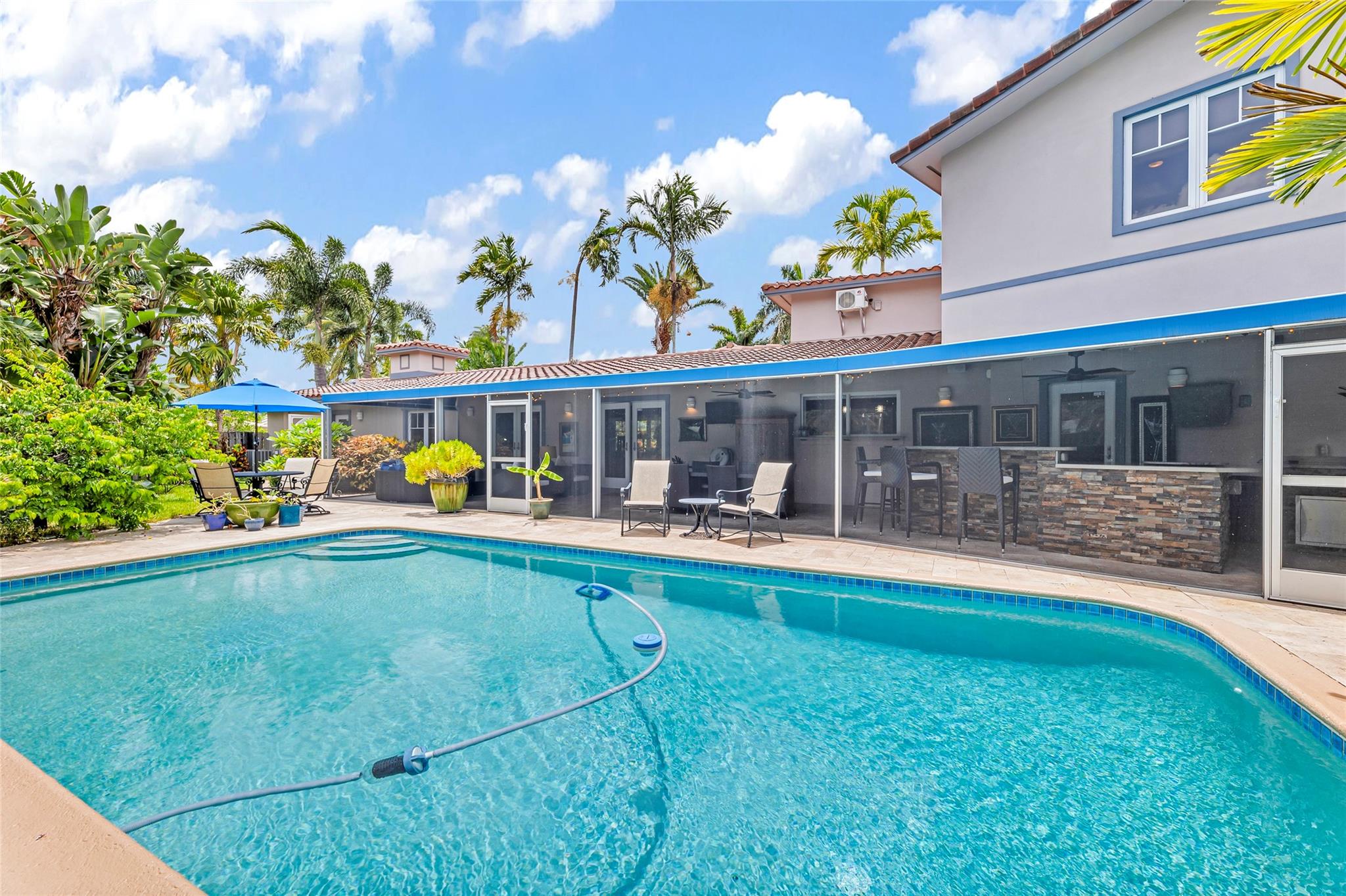 Pool surrounded by lush vegetation and easily accessible from large screened in with living, dining, bar and kitchen areas.