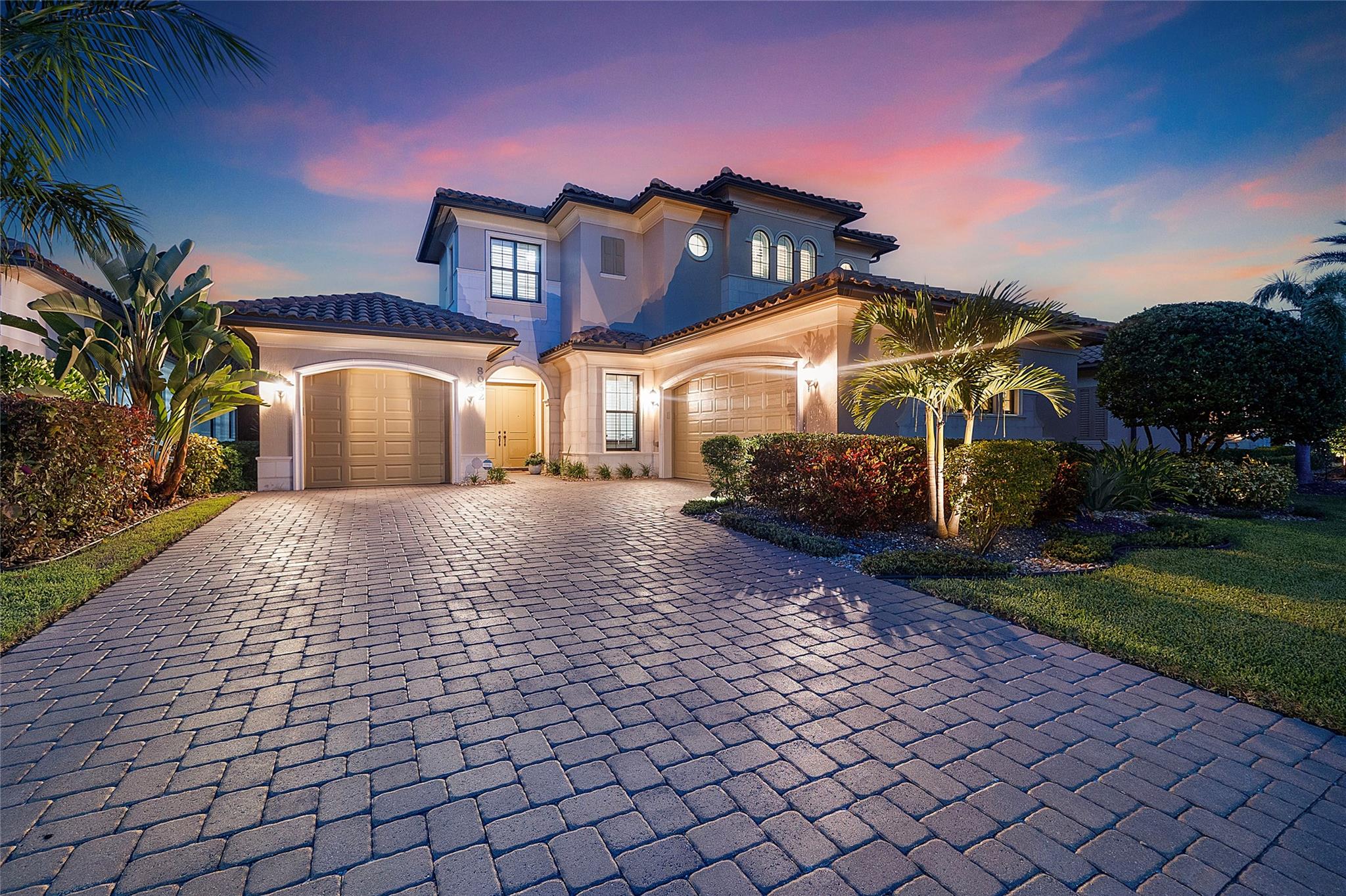 Osprey Lake newer home elevation at night time view with front pavered driveway & 3 car garages