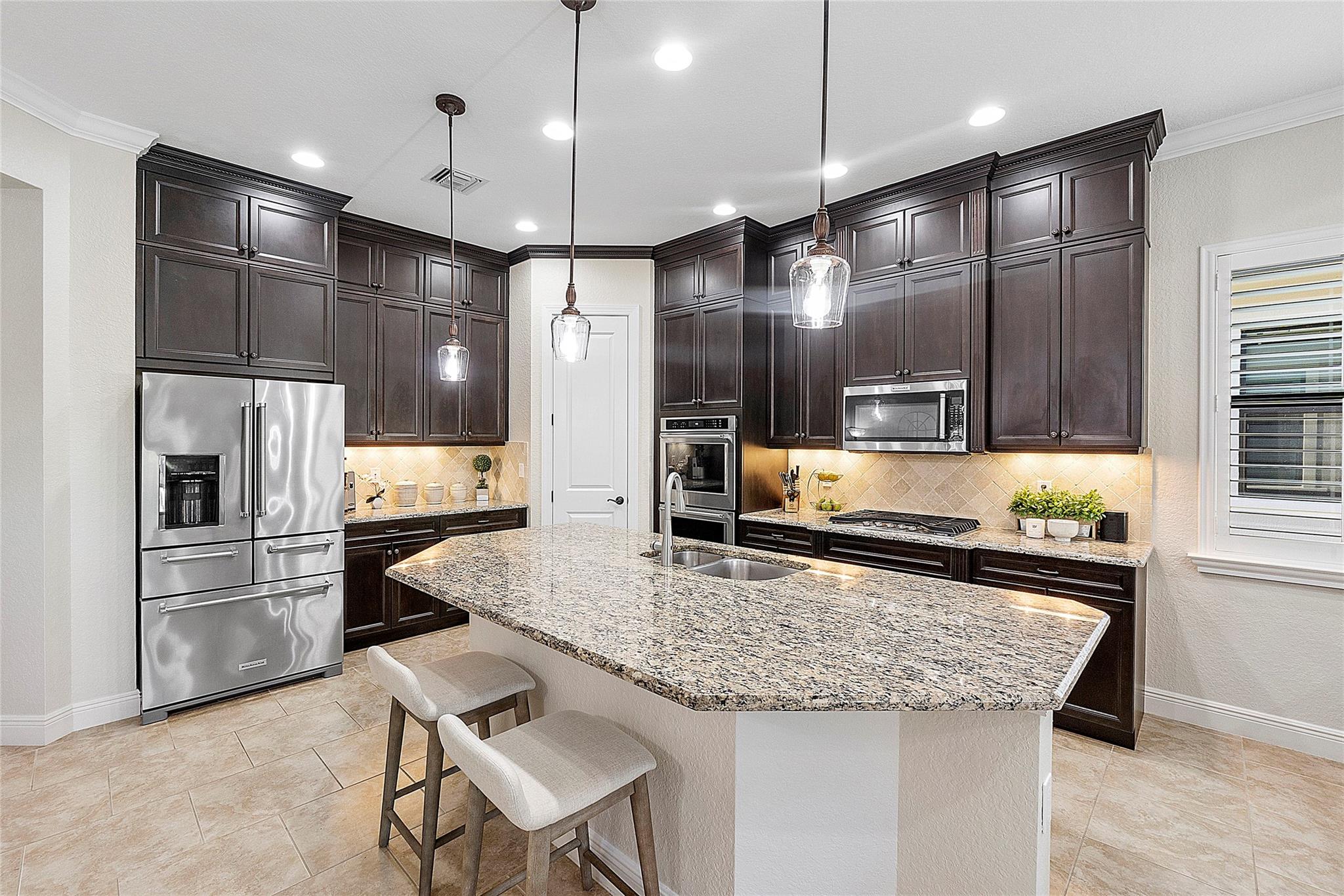 Pretty kitchen with center island counter, Tumble backsplash, Gas stove, stainless double ovens, fridge & microwave,