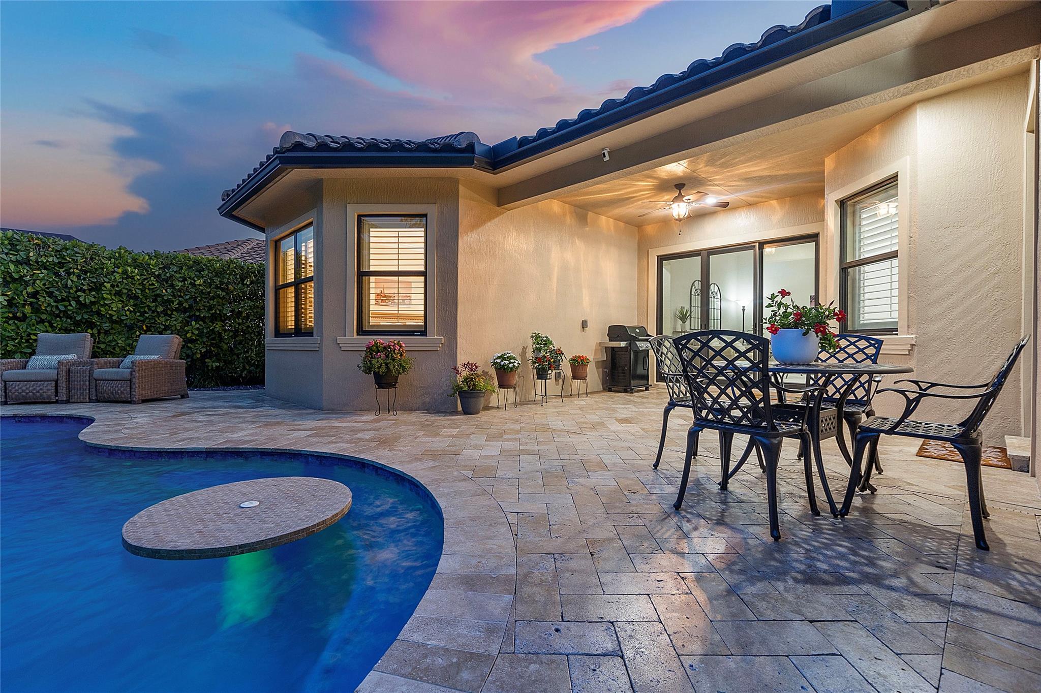 Travertine marble patio pavers surround the heated pool with matching interior cocktail or lunch table and bench inside the pool as an added upgrade