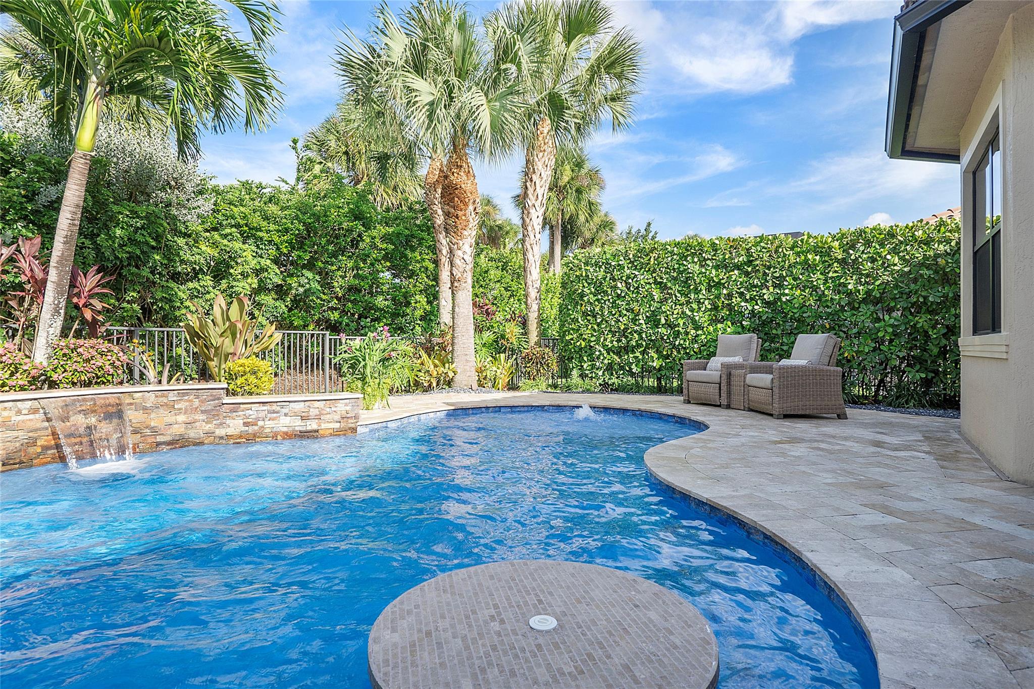 Pool and waterfall with fully fenced in tropical garden