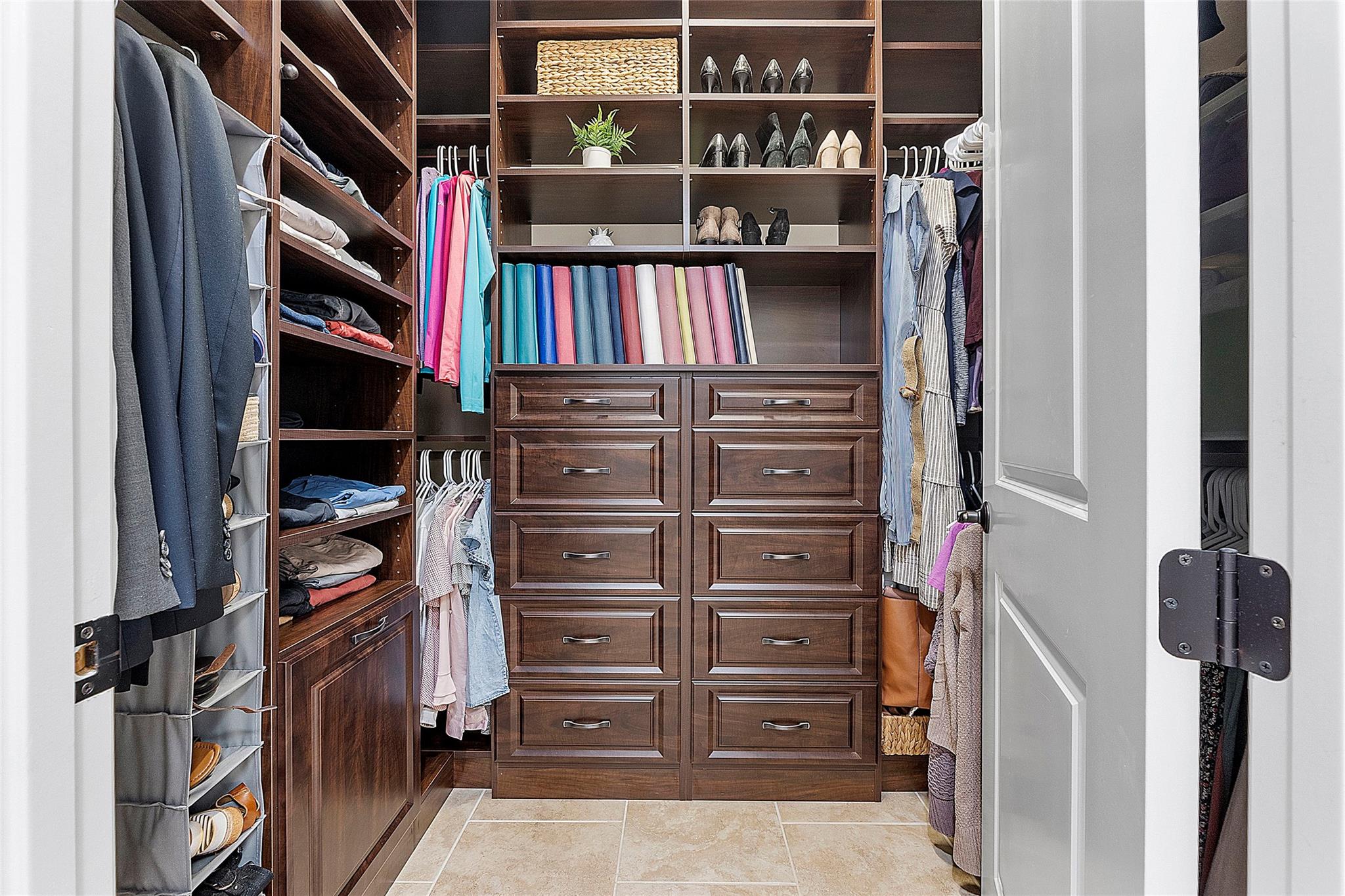 Walk-in custom cabinetry closets with ample storage and linen basket