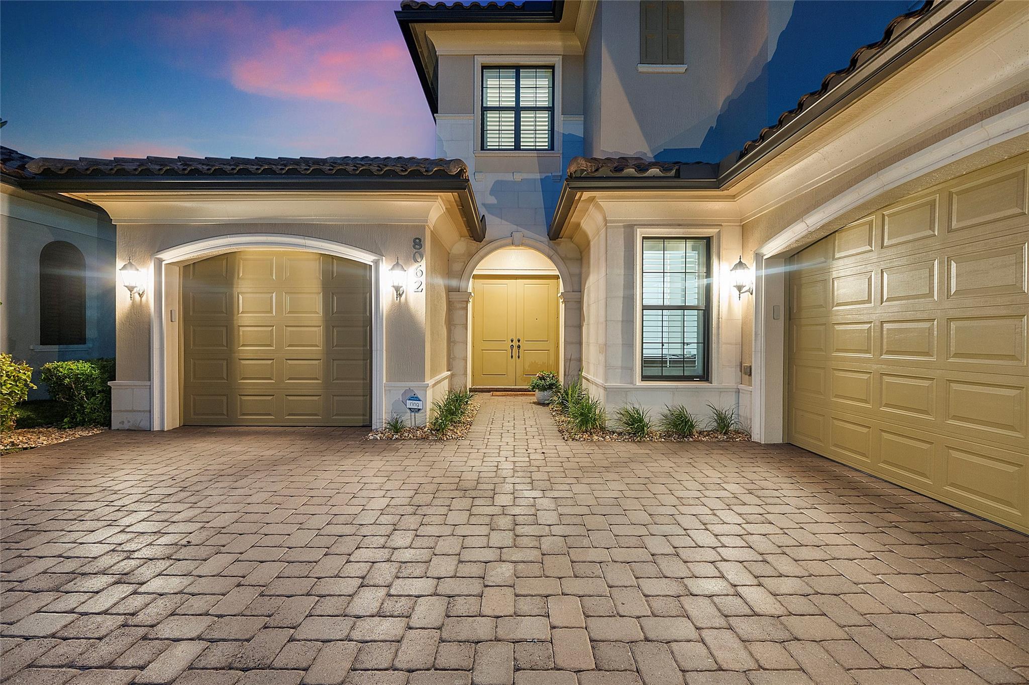 Entryway lit up for guests arriving and leaving, separate garage interior and exterior entryways on either side of the double entryway doors