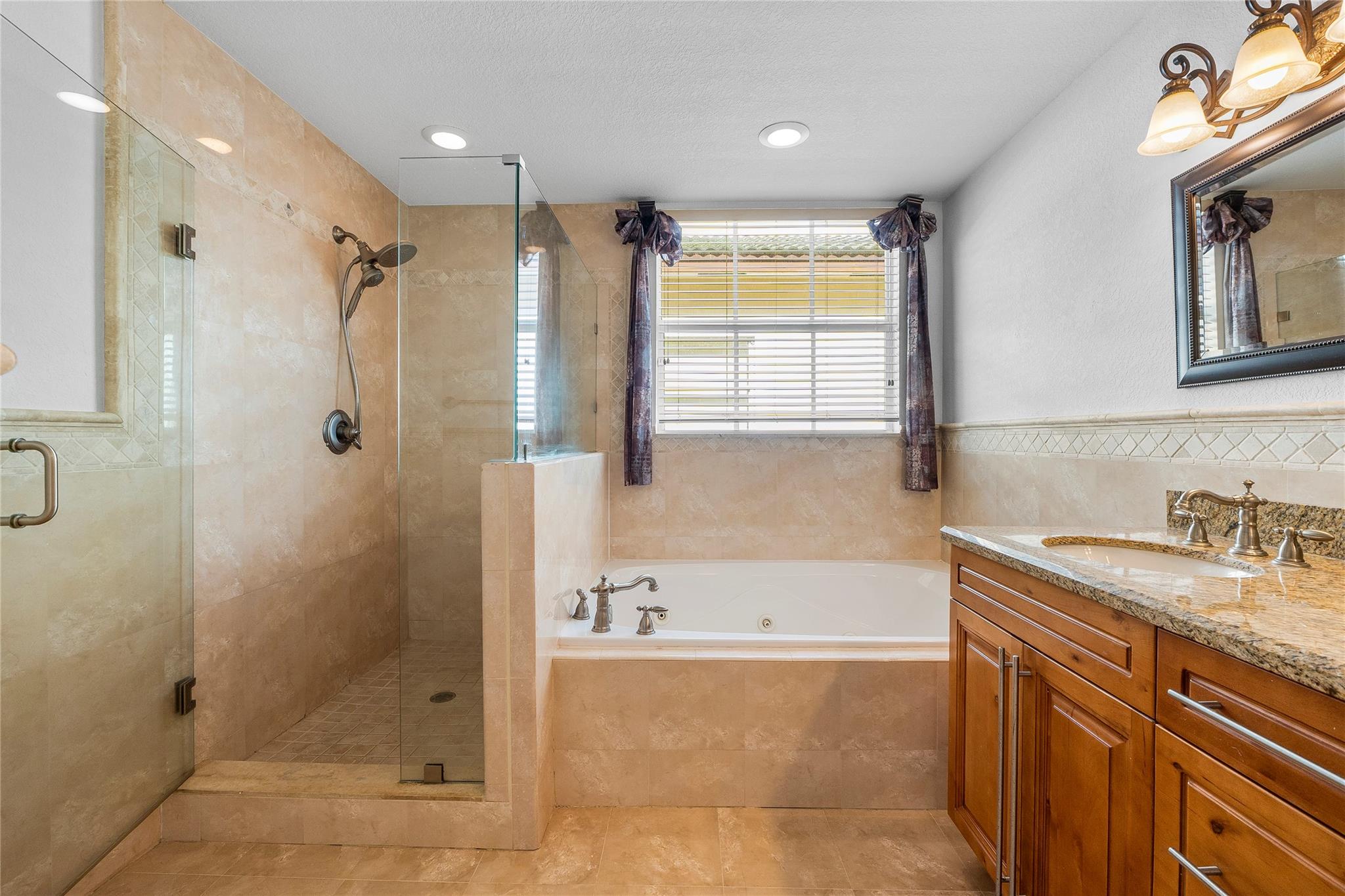 Large primary suite bathroom with dual sinks, shower and jacuzzi tub.