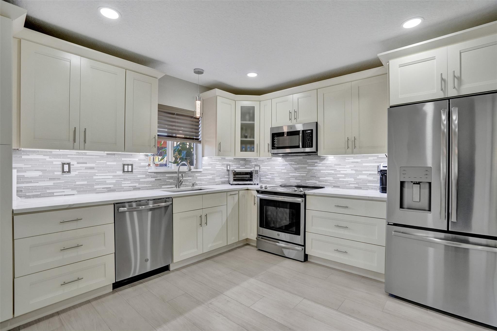 Modern chef's kitchen with quartz countertops and SS appliances