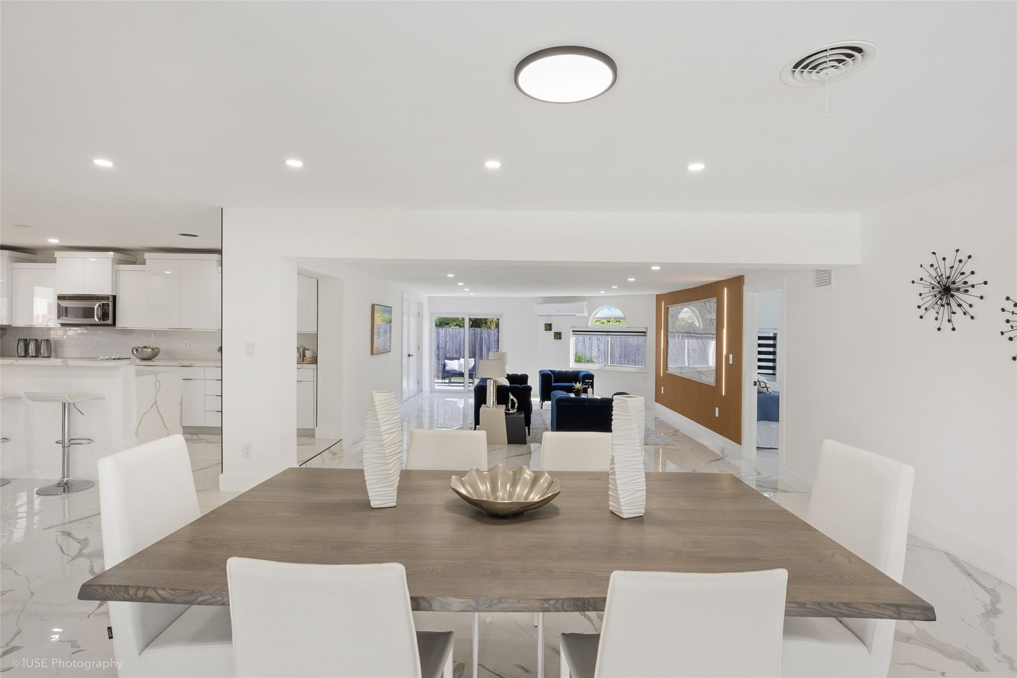 Open concept: kitchen to the left, dining area in front, living area in background with impact door to patio & pool.