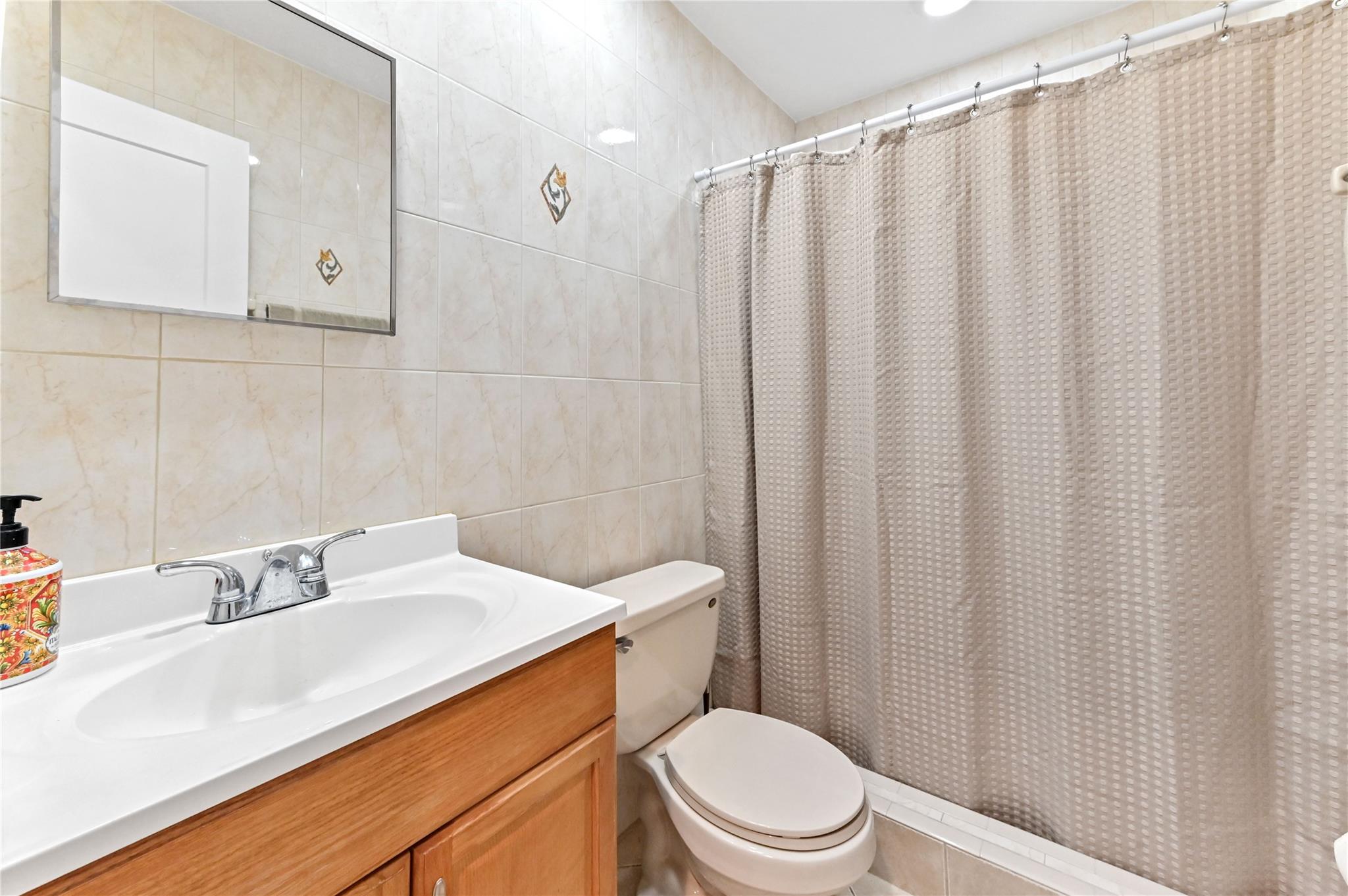 Guest bathroom has shower with designer wall tile