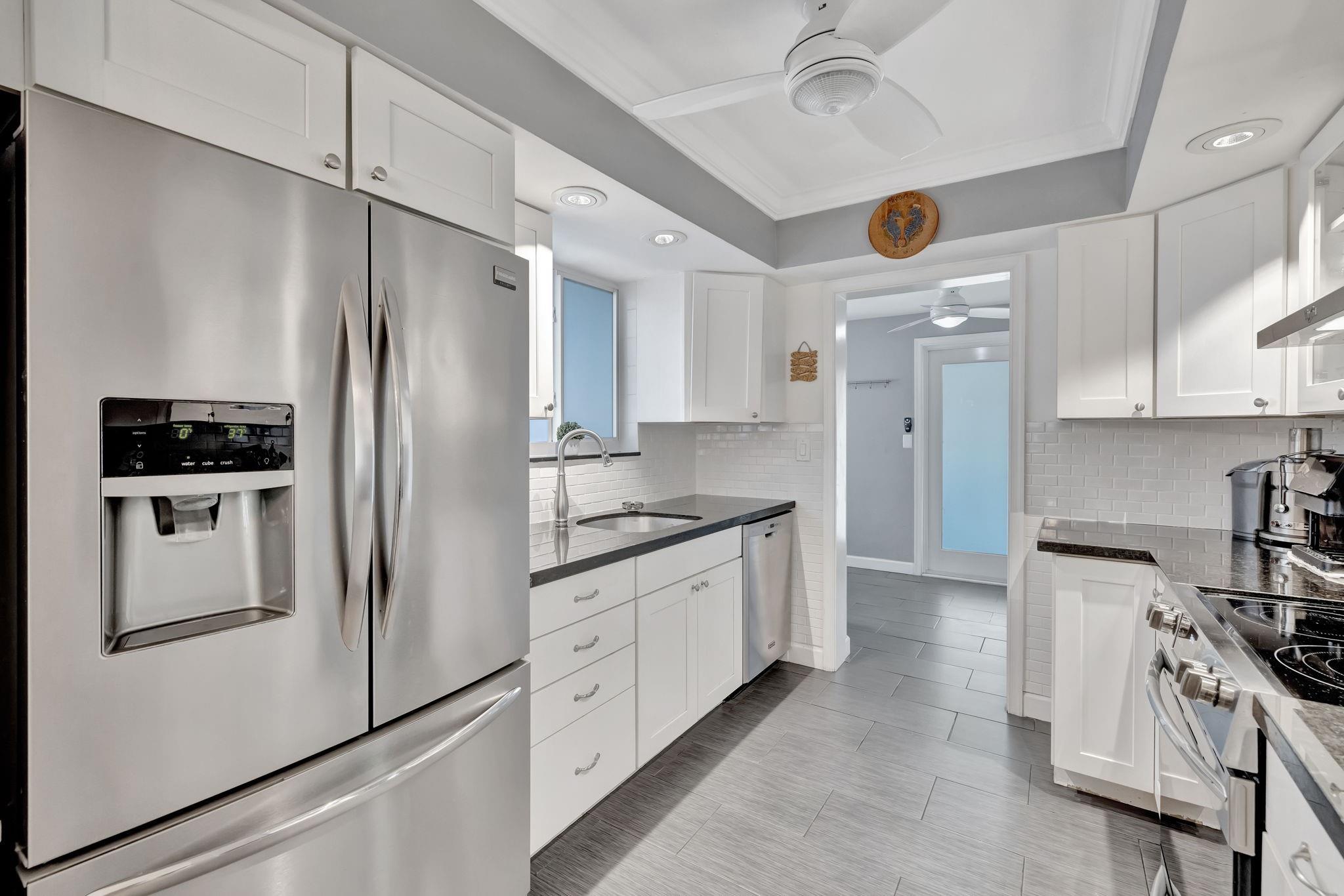 The modern kitchen features white shaker cabinets, a subway tile backsplash, stainless steel appliances.