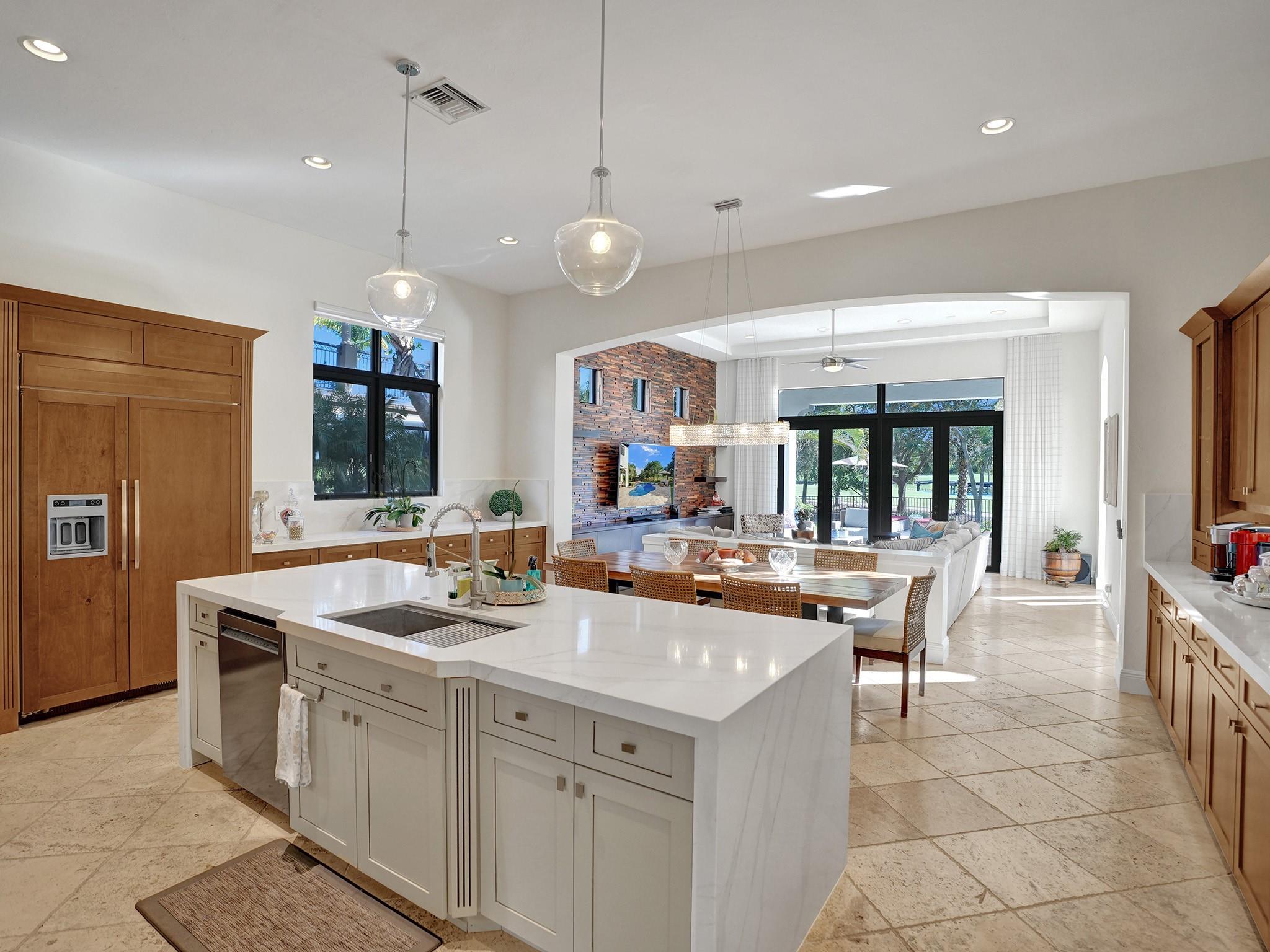The island contrasts with the other cabinets, showcasing a stunning waterfall white quartz top—a central focal point.