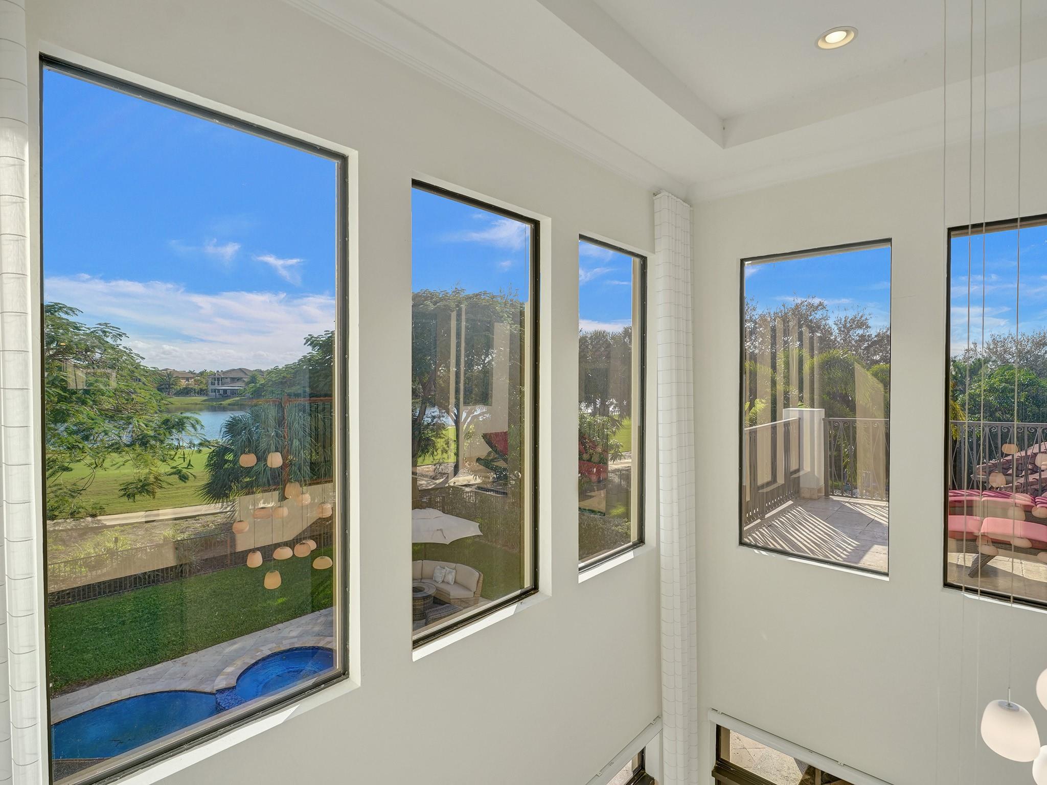 Serene views everywhere. Windows open to a terrace with marble, sunlight, and a pool view.