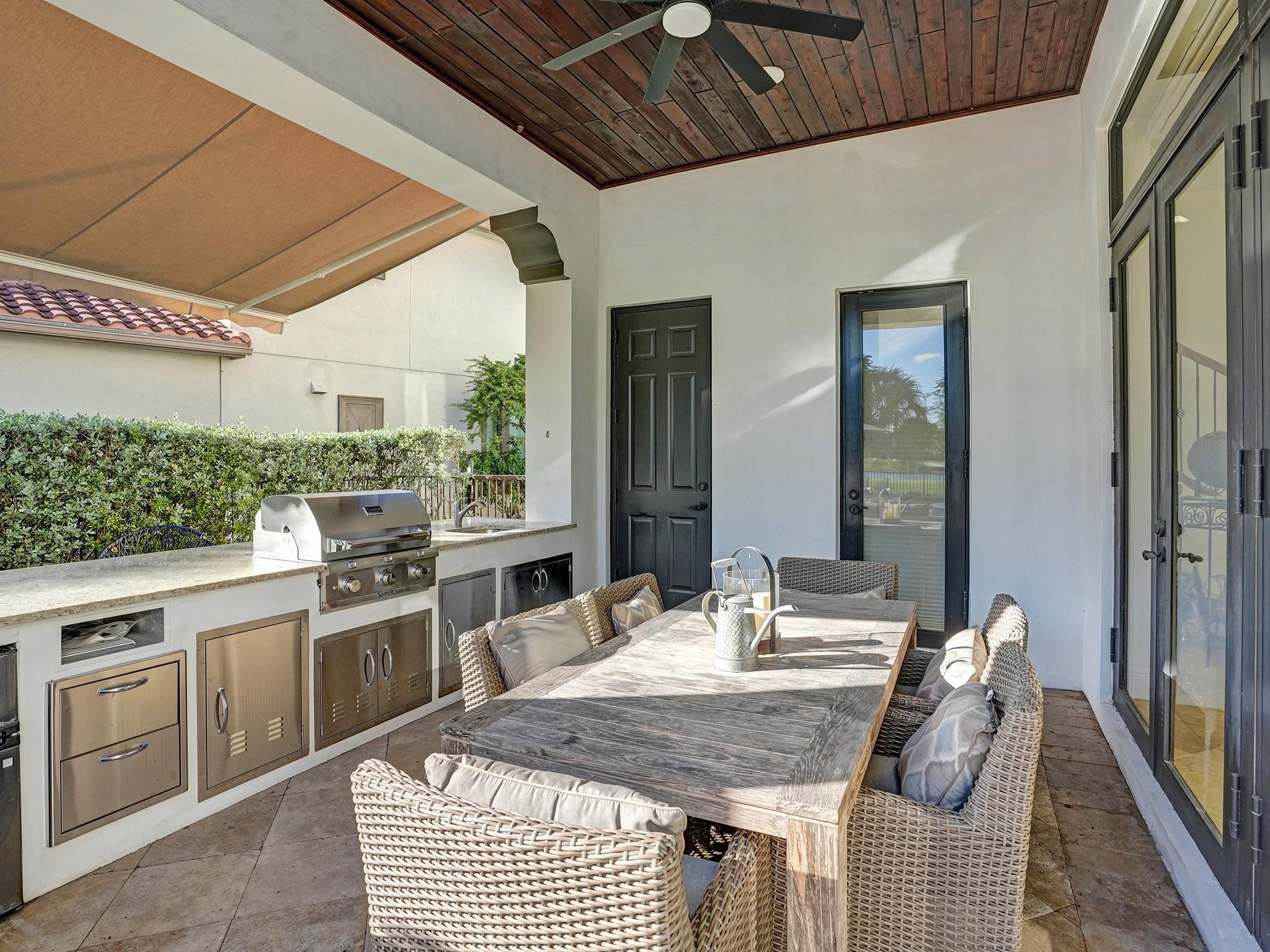 Second covered patio with wood panels, full kitchen, bar, cabana bath, and storage room for outdoor items.