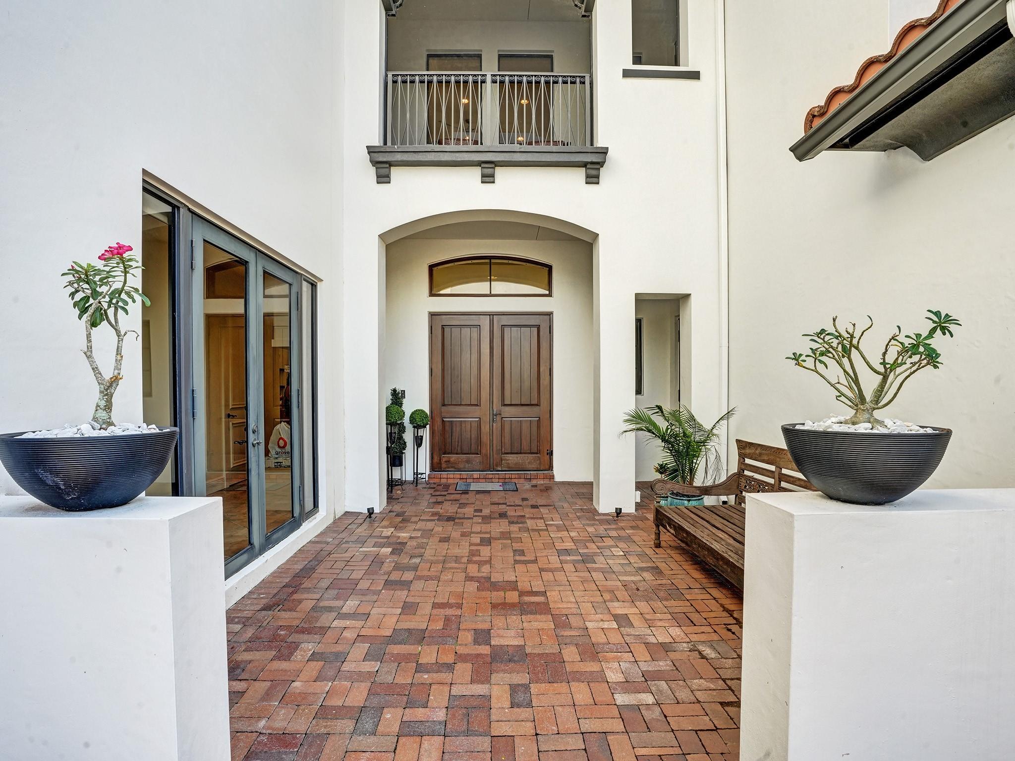 A small courtyard welcomes you. On your left, an entrance leads to the office, while the front door, adorned with a balcony above, offers another access point.