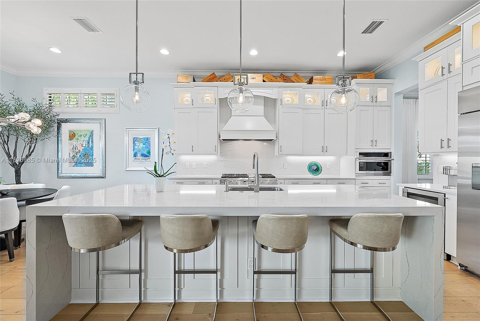 Perfectly situated in the center of Artistry, this home offers a peaceful water view and desirable southern exposure, filling the interior with natural light throughout the day. With an easement between you and the next-door neighbor, you'll enjoy a greater sense of privacy and space, rarely found in this community. Inside, tasteful upgrades and designer finishes create a polished yet comfortable atmosphere. White oak flooring, quartz surfaces, beautiful crown molding, and upscale fixtures are featured throughout. A versatile front room sets the stage for entertaining or formal gatherings, while the chef's kitchen delivers top-tier performance with GE Monogram appliances, a 6-burner gas range with griddle, three ovens, an oversized waterfall island, wine cooler, and upgraded cabinetry.