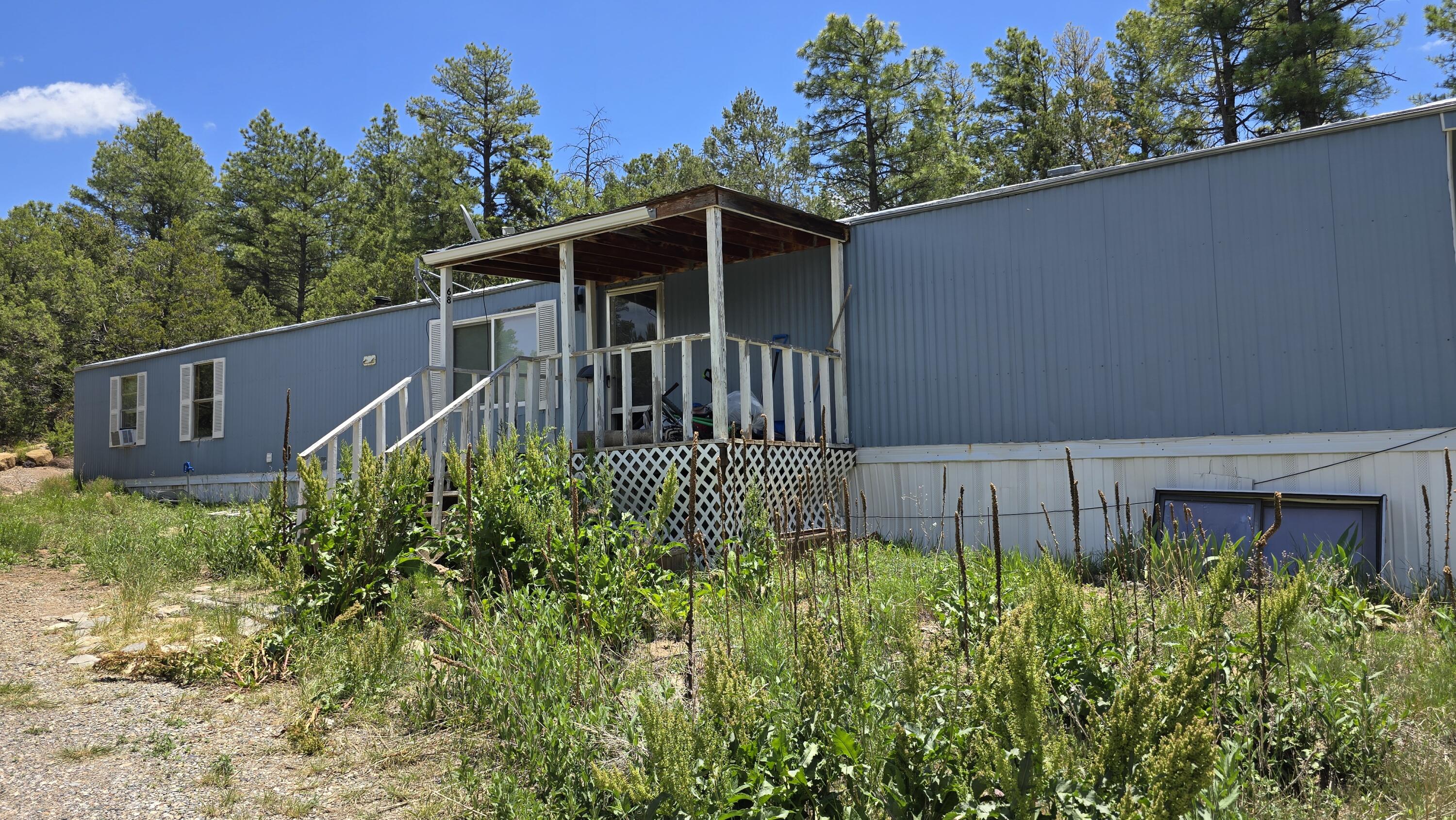 Beautiful wooded 2 acres just 25 min from Albuquerque! Includes manufactured home with 3 bedrooms, 2 full baths and an open living/dining/kitchen concept! Furnace and water heater 3 yrs old, private well with 500 gal storage tank. Screened back patio too! Seller will consider a REC with 20% down.