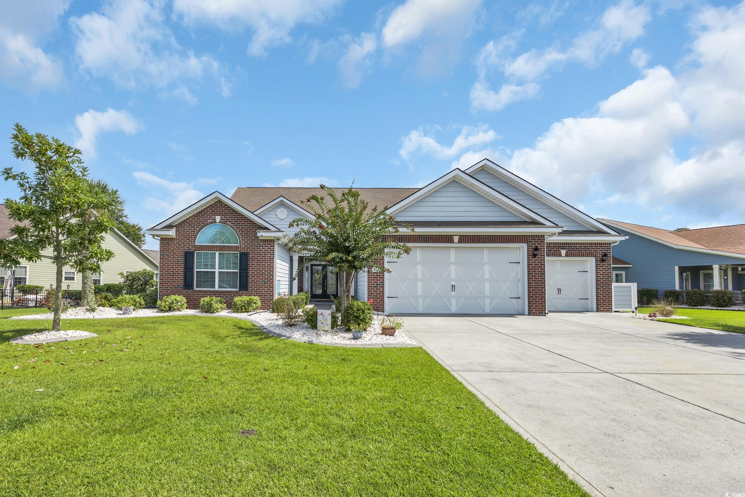 View of front of home with a front lawn, driveway, brick siding, and an attached garage