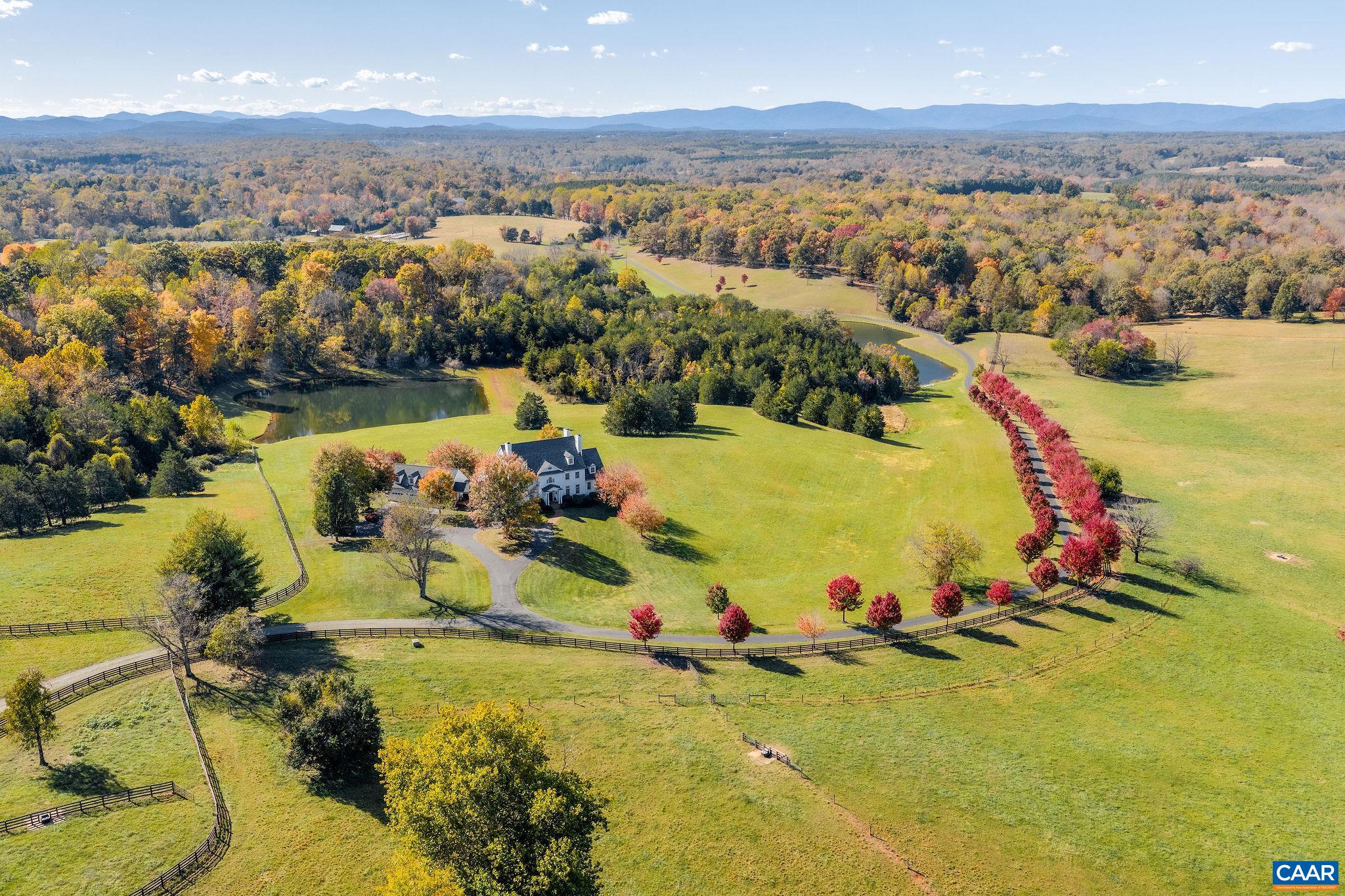 This extraordinary Georgian estate is set on 179 acres with two ponds, seven natural springs, and two barns, offering timeless elegance in a truly remarkable setting with additional subdivision and vineyard potential. Designed for both entertaining and everyday living, the home blends historic charm with modern comfort, all while capturing breathtaking mountain views from nearly every room. The main level offers a graceful mix of formal and casual spaces, including a first-floor primary suite, antique heart pine floors, and a handsome study. Upstairs, a second primary suite with a renovated bath enjoys panoramic vistas, complemented by three additional bedrooms with en-suite baths. The lower level is designed for recreation with a large screen viewing area, wet bar, billiards room and provides a welcoming guest bedroom, full bath and office. Seven fireplaces add warmth and character. Outdoor living boasts a free-form pool, wide porches, and sweeping vistas. A four-car garage with portico has a second floor roughed-in. Every detail reflects quality and sophistication, making this estate a rare opportunity where land, luxury, and lifestyle come together, and every feature is designed to elevate gracious country living.