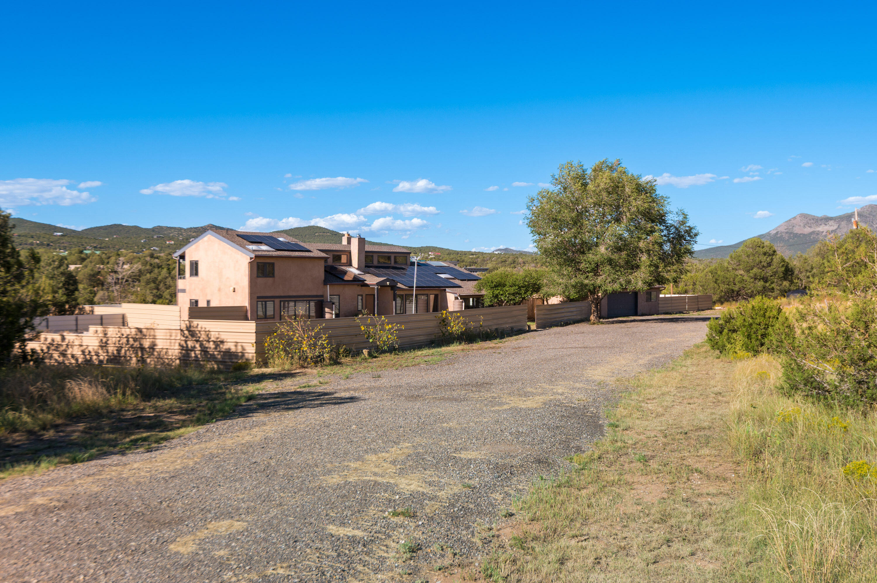 2.25% VA ASSUMABLE LOAN!  Off-the-grid, fully self-contained estate tucked away on 6.5 acres in the Sandias. Purposefully designed for sustainable living, it offers its own power, water, gardens, livestock area, water catchment pond, & 2-car garage w/ shop & service pit.  A 3,000-gal. water storage tank, owned solar panels, & 3 TESLA power wall batteries, provide efficiency & independence, while established garden beds & space for animals invite homestead lifestyle. Inside, soaring vaulted ceilings, clerestory windows, fireplaces, & sunroom fill the home w/ warmth & light. Versatile basement flex space adds room for work or play. Here, privacy & mountain views combine w/ modern comforts, making it the ultimate retreat for those seeking freedom, self-reliance, & connection to the land.