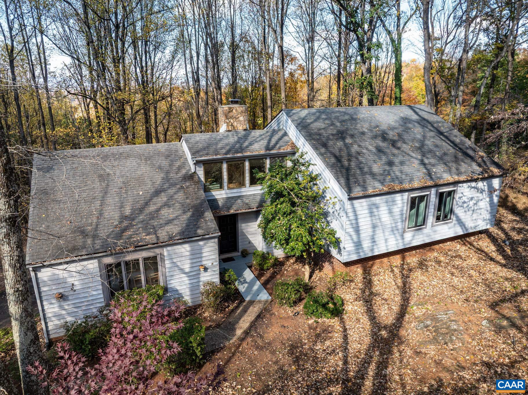 Nestled in the desirable Ashcroft neighborhood, a unique mountainside setting located minutes to Downtown, I-64, hospitals, and shopping. Natural light abounds in this stunning, spacious contemporary on 1.5 private acres, with expansive decks framed by seasonal Blue Ridge views and mature trees. Fenced yard is perfect for pets. This 4BR/3BA home features soaring ceilings, and an open floor plan with dramatic stone fireplace in the living room. The chef in your family will enjoy the kitchen with its large island ideal for gathering and great for entertaining. The primary bedroom suite evokes the feel of a treehouse retreat, featuring large walk-in closet, luxury jacuzzi bath, and its own private deck for enjoying your morning coffee among the treetops and mountains. Generously sized bedrooms, with large closets and ceiling fans. The lower level features a large family room with built-in shelves, ideal for a theater or playroom, the fourth bedroom or guestroom, and full bath with laundry. Expansive two-car garage with cabinets and workspace. With access to Ashcroft’s miles of walking trails, pool, tennis, and clubhouse, this home offers the best of mountain living with the convenience of town just minutes away.