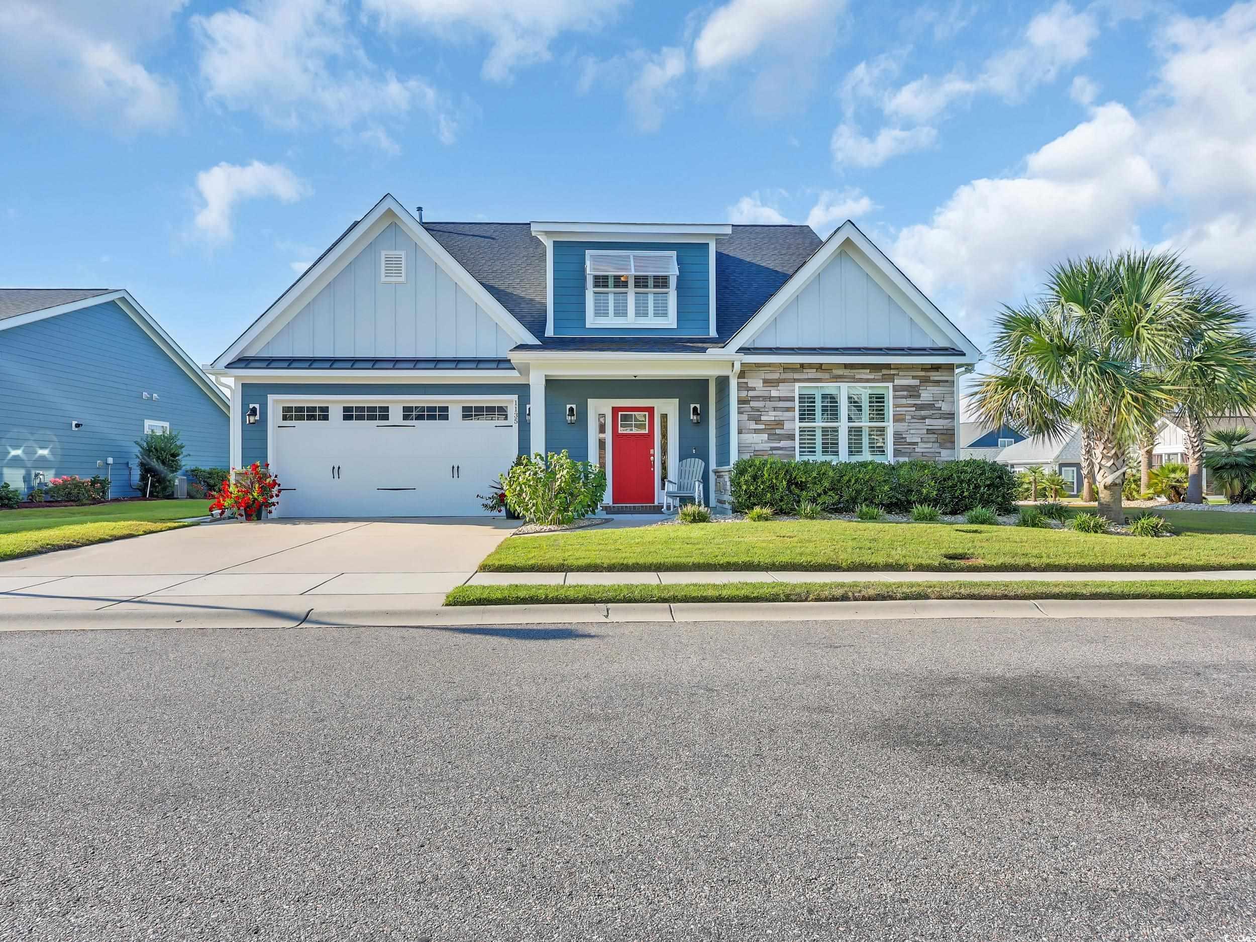 Craftsman-style home with board and batten siding, a front lawn, driveway, covered porch, and stone siding