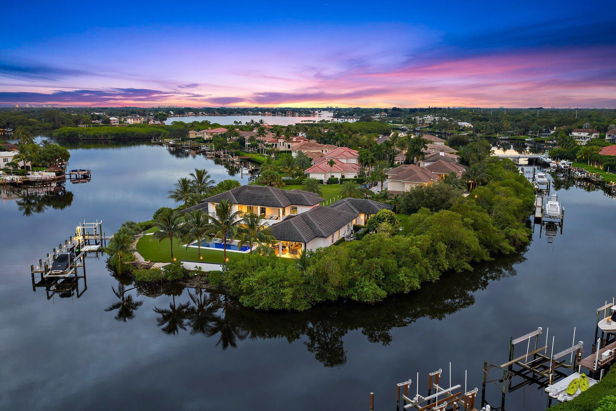 Located on a peninsula lot of 1.33 acres with 500 feet of deep waterfrontage on three sides with no fixed bridges, this truly is one of the finest waterfront properties in our area.  Custom built in 2021 by Ocean Blue Custom Homes, this signature estate in the luxury, gated community - The Islands of Jupiter, meets the demands of the most sophisticated clients.  Floor to ceiling walls of glass brings the outside in, offering a ''light and bright'' texture to a modern coastal interior palette.  Views to the pool with spa, summer kitchen with bar, dock with two lifts, professional landscaping, and expansive backyard with endless artificial turf; all define a dreamlike setting for a family retreat.  The current owner made the following additions/upgrades within the past 12 months: 24 KW generator, electric/hurricane screens, new pool resurfacing, under dock lights, all new light fixtures and ceiling fans, paint inside and out, garage storage cabinets, luxury flooring, new kitchen island counter top &amp; back splash, bar top, primary bath counter top, and two sets of washers and dryers - one set for each floor.  The primary suite and guesthouse are on the first floor, and three guest suites plus an expansive loft area and second laundry room occupy the second floor.  Call today to view this amazing property that could be yours!