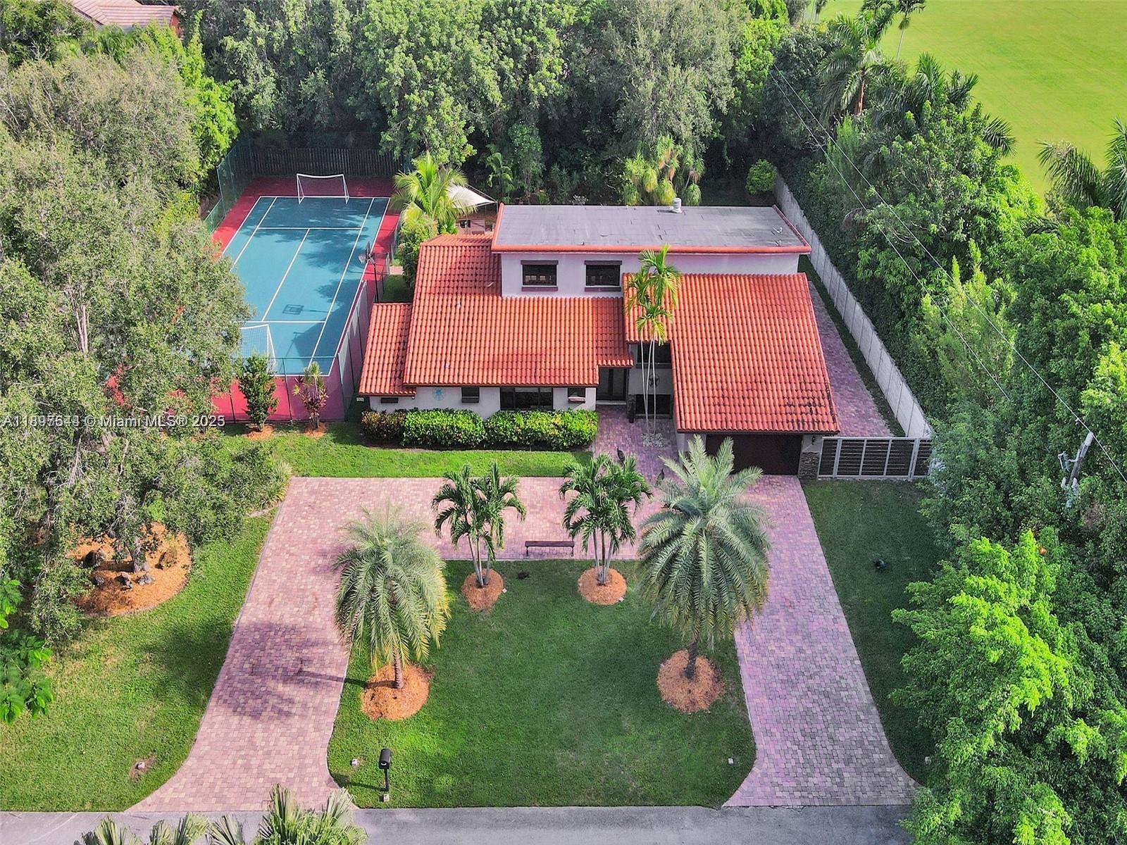 Escape to your own private paradise in this stunning Palmetto Bay estate, where luxury meets lifestyle on over half an acre at the end of a peaceful cul-de-sac. This dream home provides  resort-style living with a sparkling pool, summer kitchen, covered patio, and your very own multi-sport court—perfect for tennis, soccer, basketball, and football. Entertain effortlessly with lush landscaping and an expansive driveway, all without the restrictions of an HOA. Inside, soaring ceilings and oversized windows fill the home with natural light, creating an airy, open feel. Why leave home when everything you need is right here? Live the American dream—your private clubhouse awaits in South Florida!