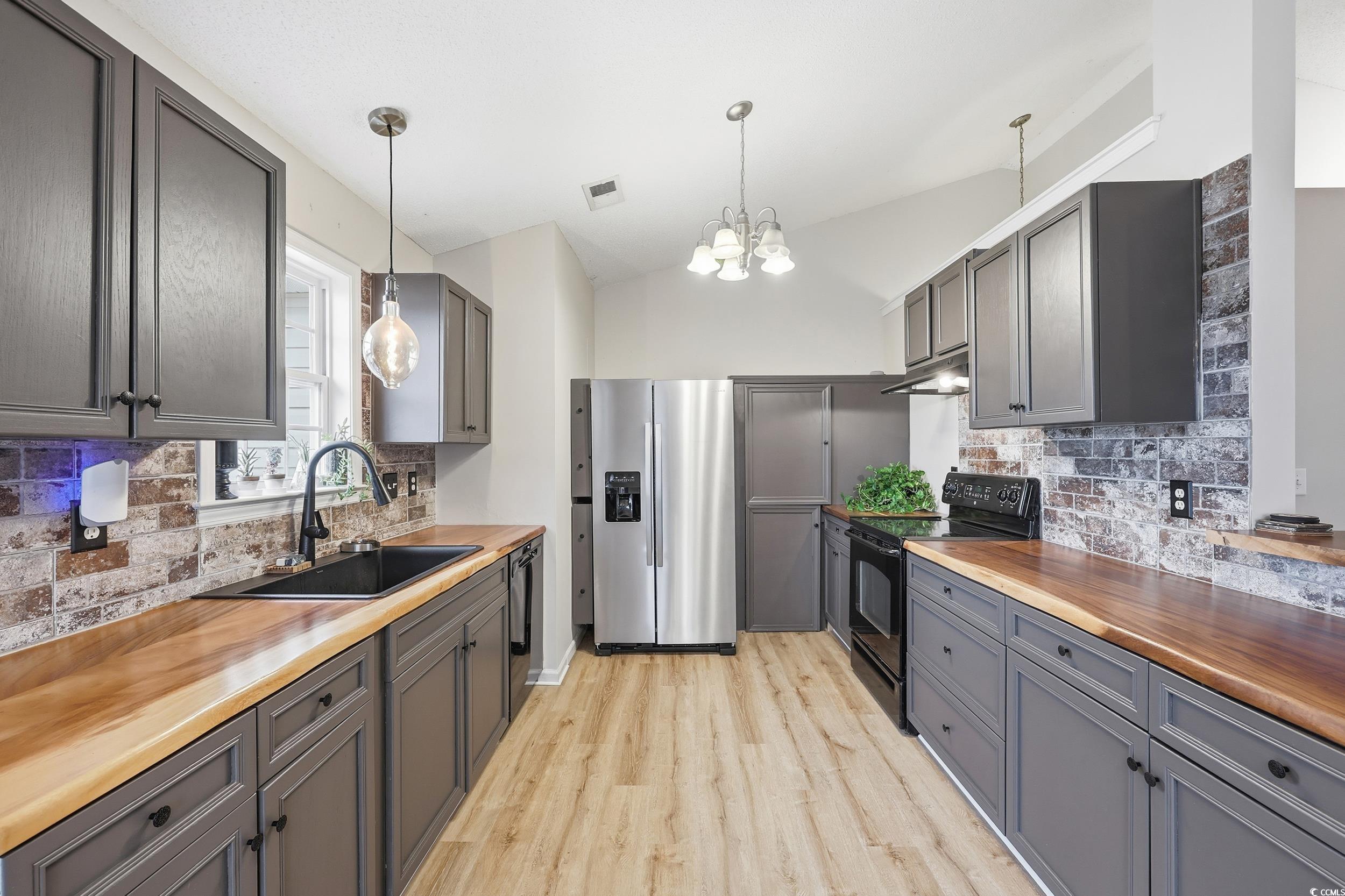 Kitchen featuring wooden counters, decorative backsplash, gray cabinets, and lofted ceiling