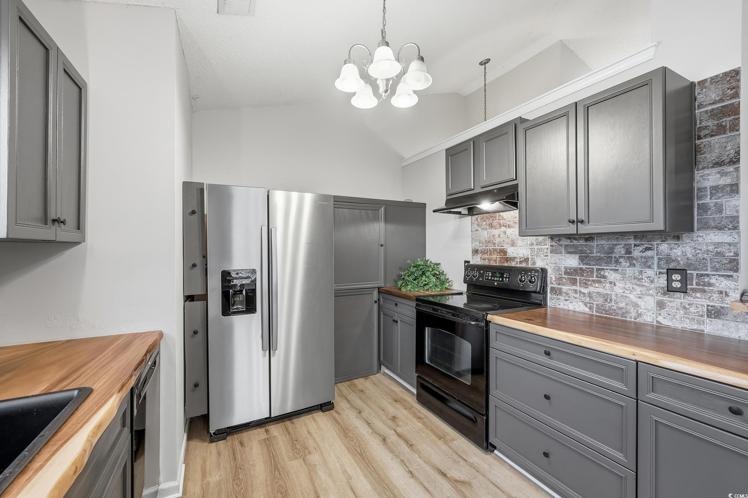Kitchen with gray cabinets, black appliances, butcher block countertops, tasteful backsplash, and decorative light fixtures