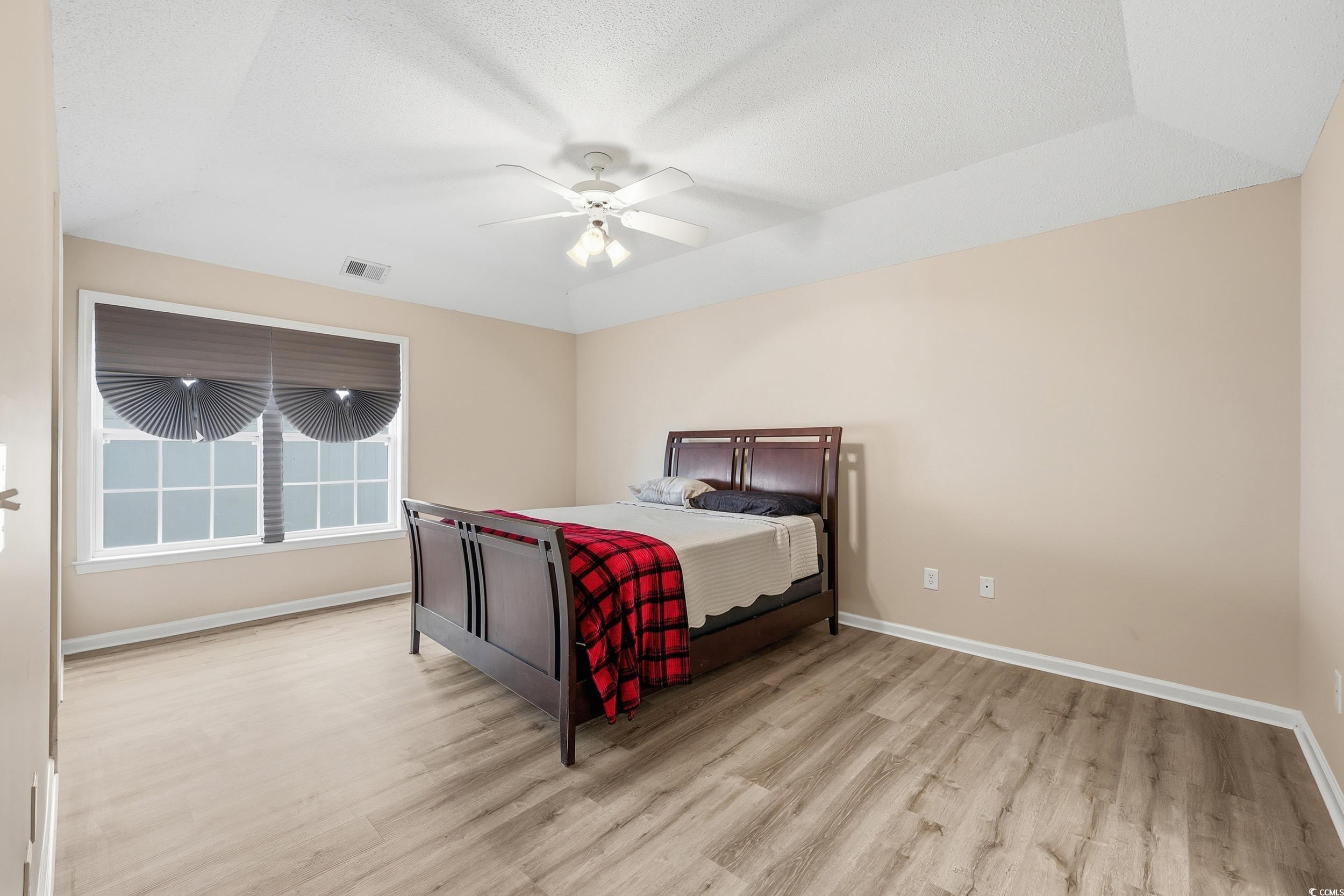 Bedroom featuring light wood-style floors, ceiling fan, and a textured ceiling