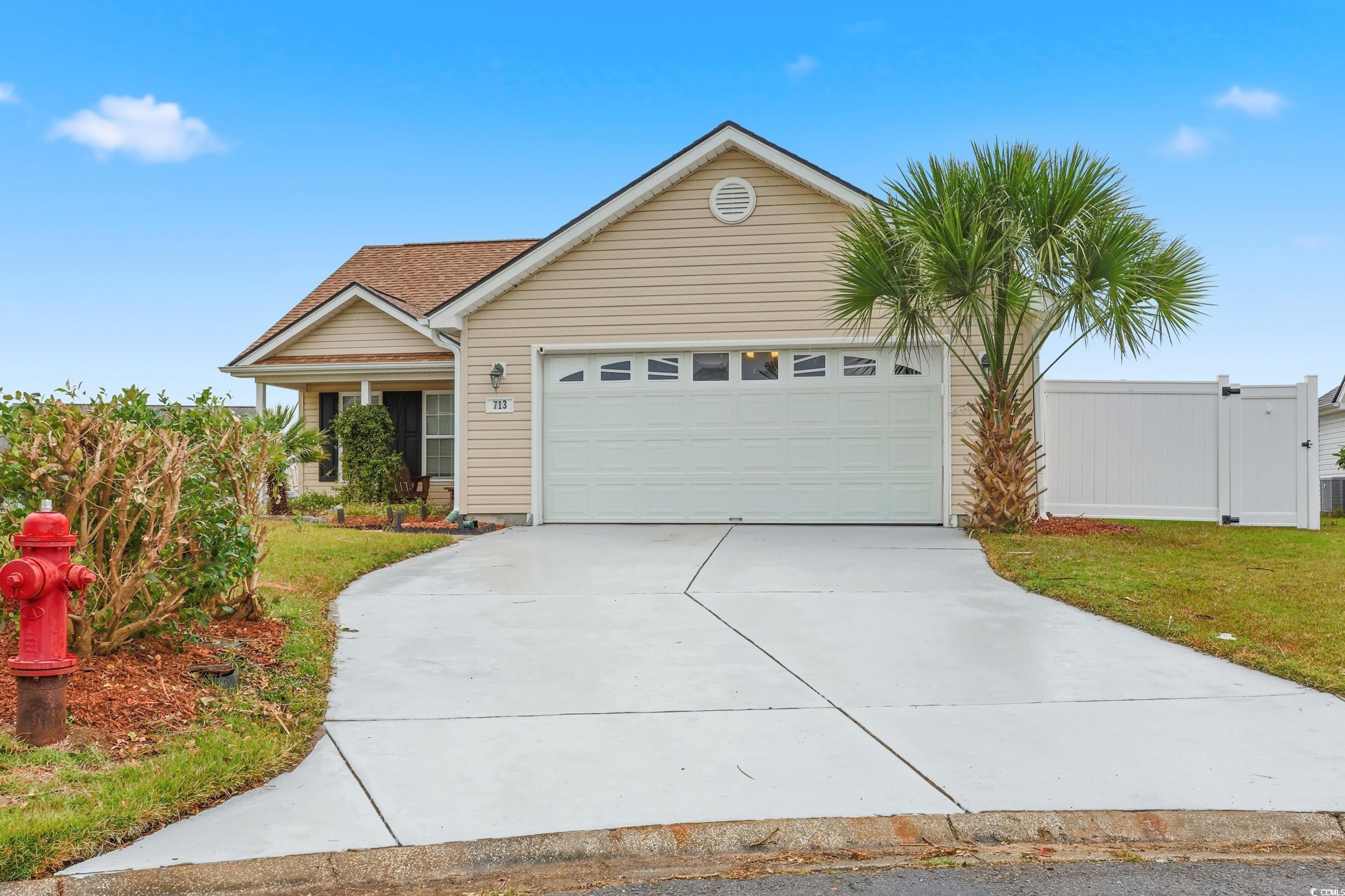 View of front facade featuring driveway, an attached garage, and a front lawn