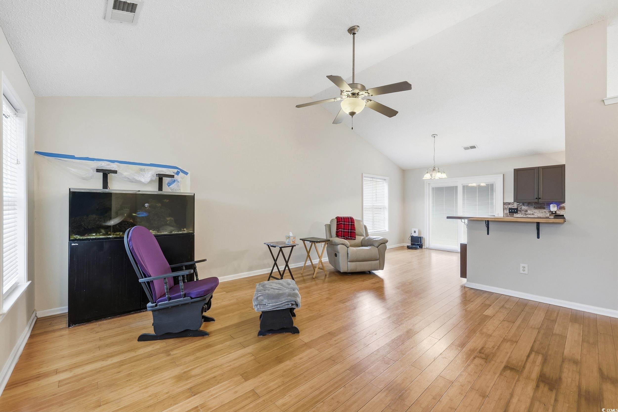Living area featuring light wood-style floors, high vaulted ceiling, and a ceiling fan