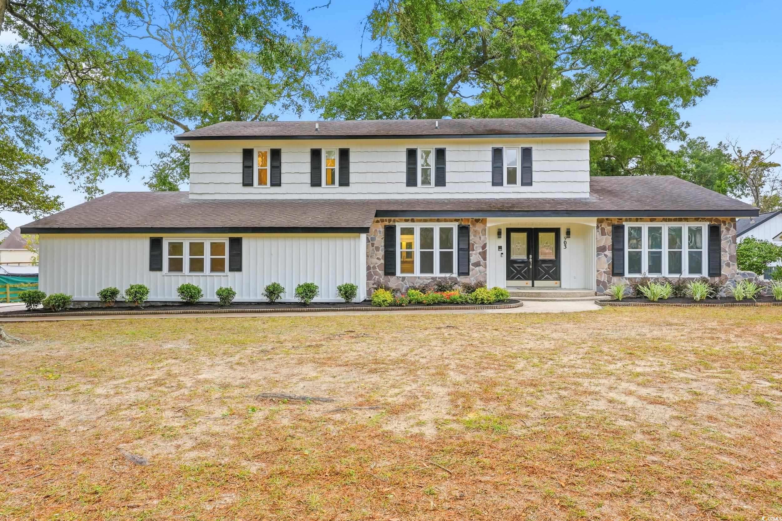 Traditional home with a shingled roof, a front lawn, board and batten siding, and a porch