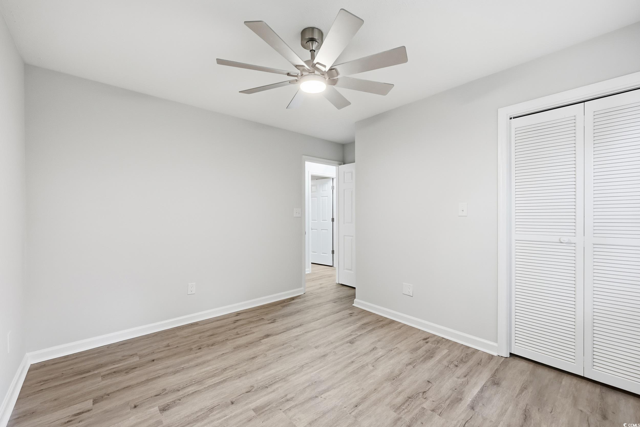 Unfurnished bedroom featuring light wood-style flooring, ceiling fan, and a closet