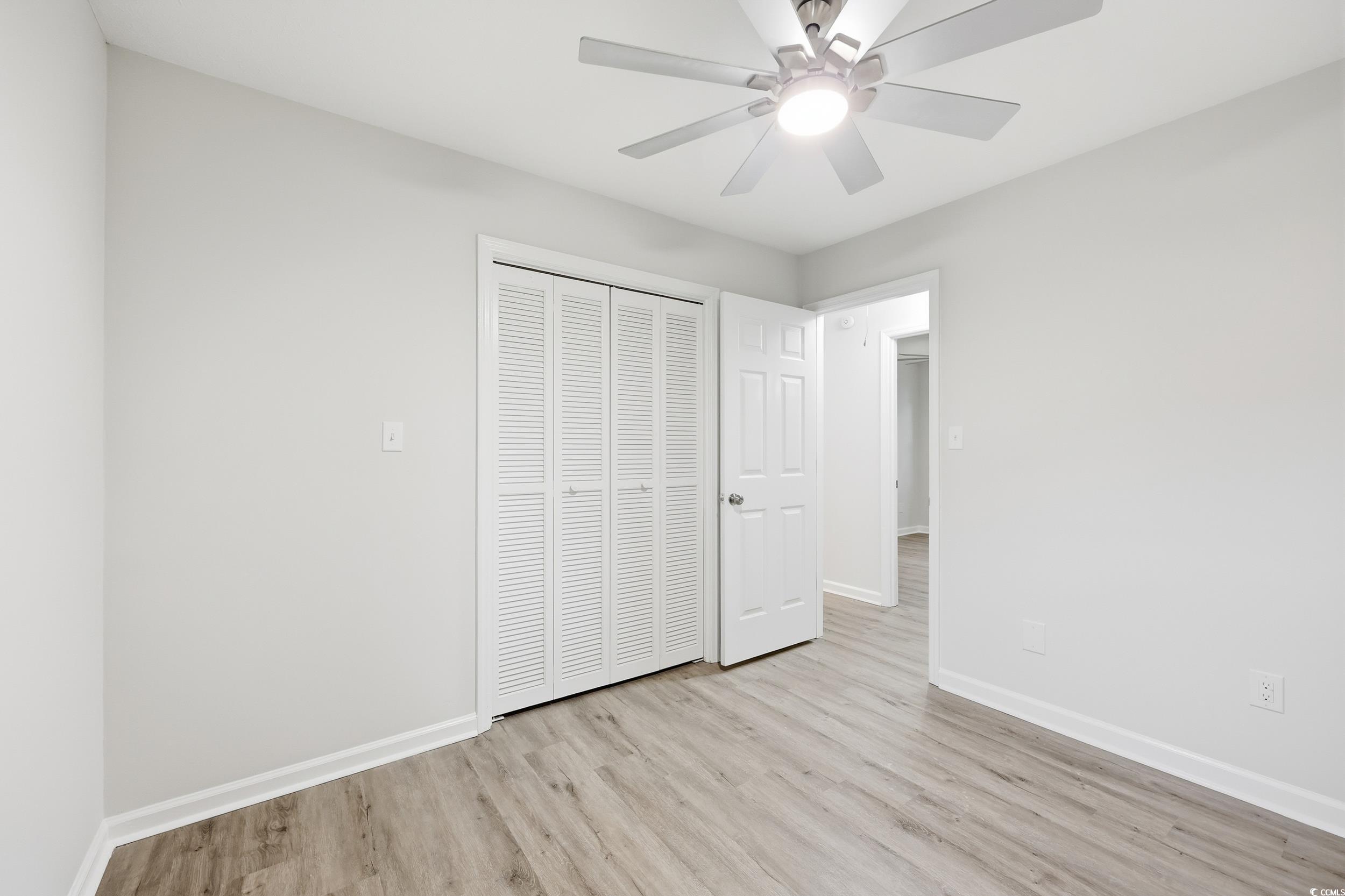 Unfurnished bedroom with light wood-type flooring, a ceiling fan, and a closet