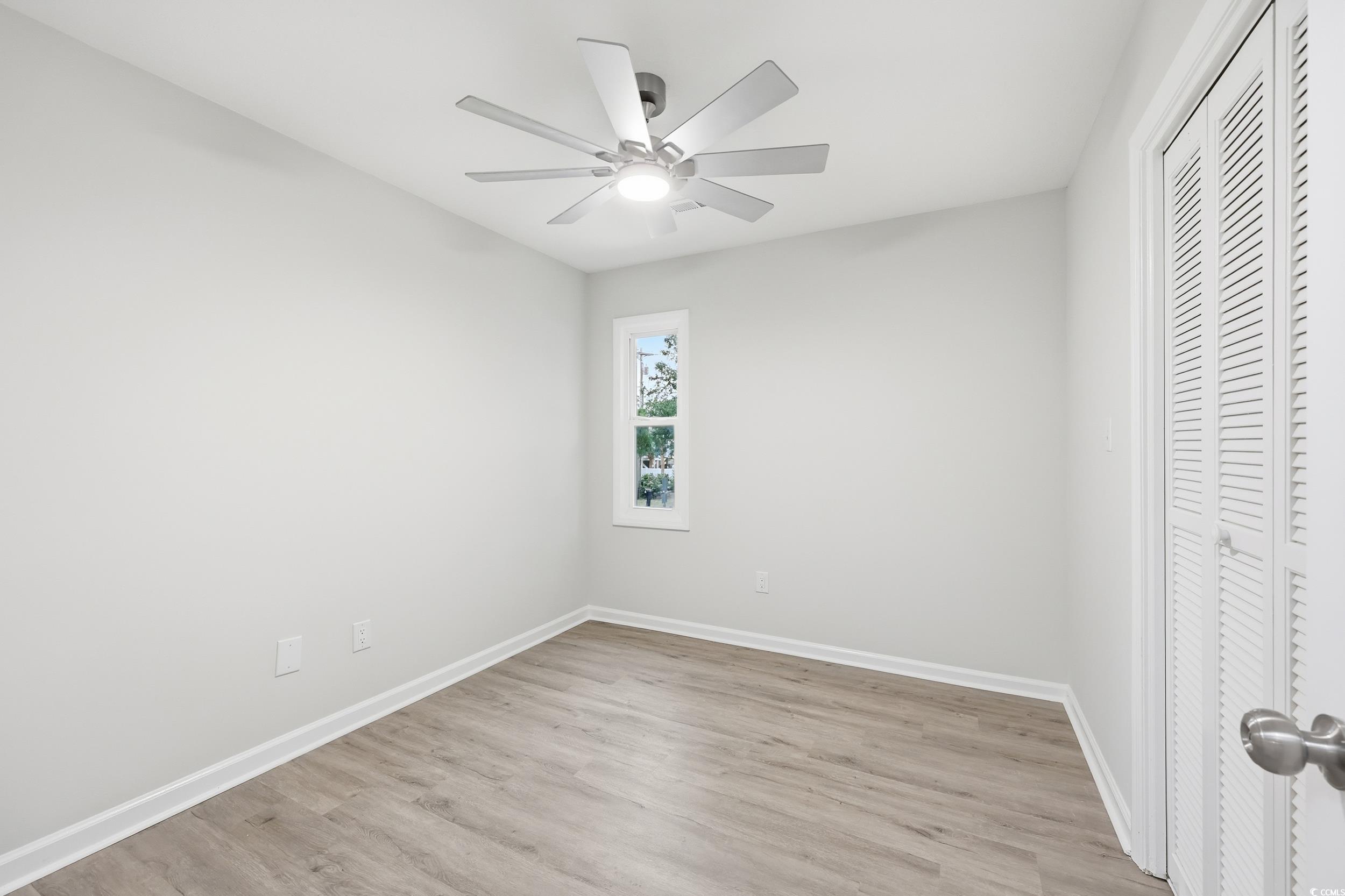 Unfurnished bedroom featuring a closet, light wood-style flooring, and a ceiling fan