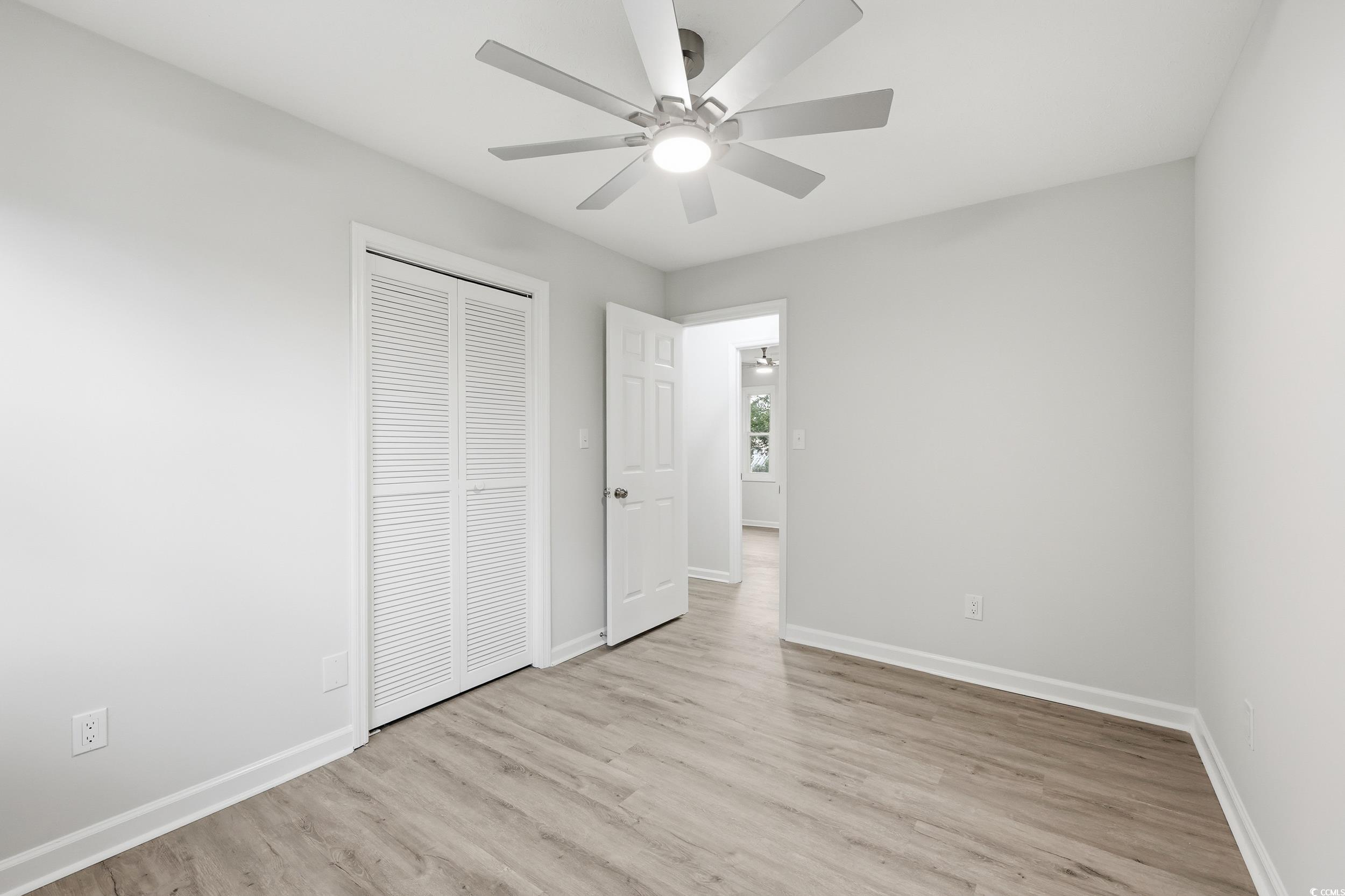 Unfurnished bedroom featuring light wood-style flooring, ceiling fan, and a closet