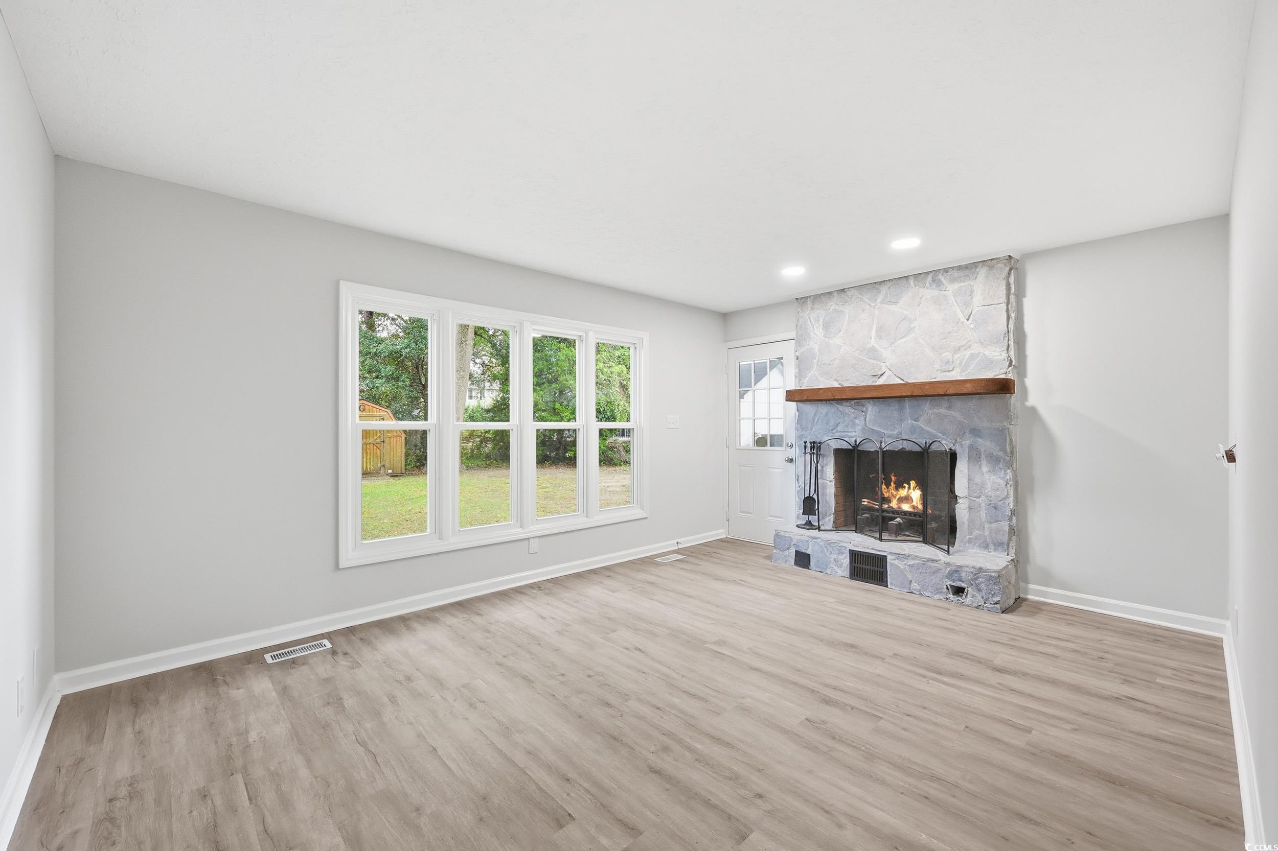 Unfurnished living room featuring a stone fireplace, light wood finished floors, and recessed lighting